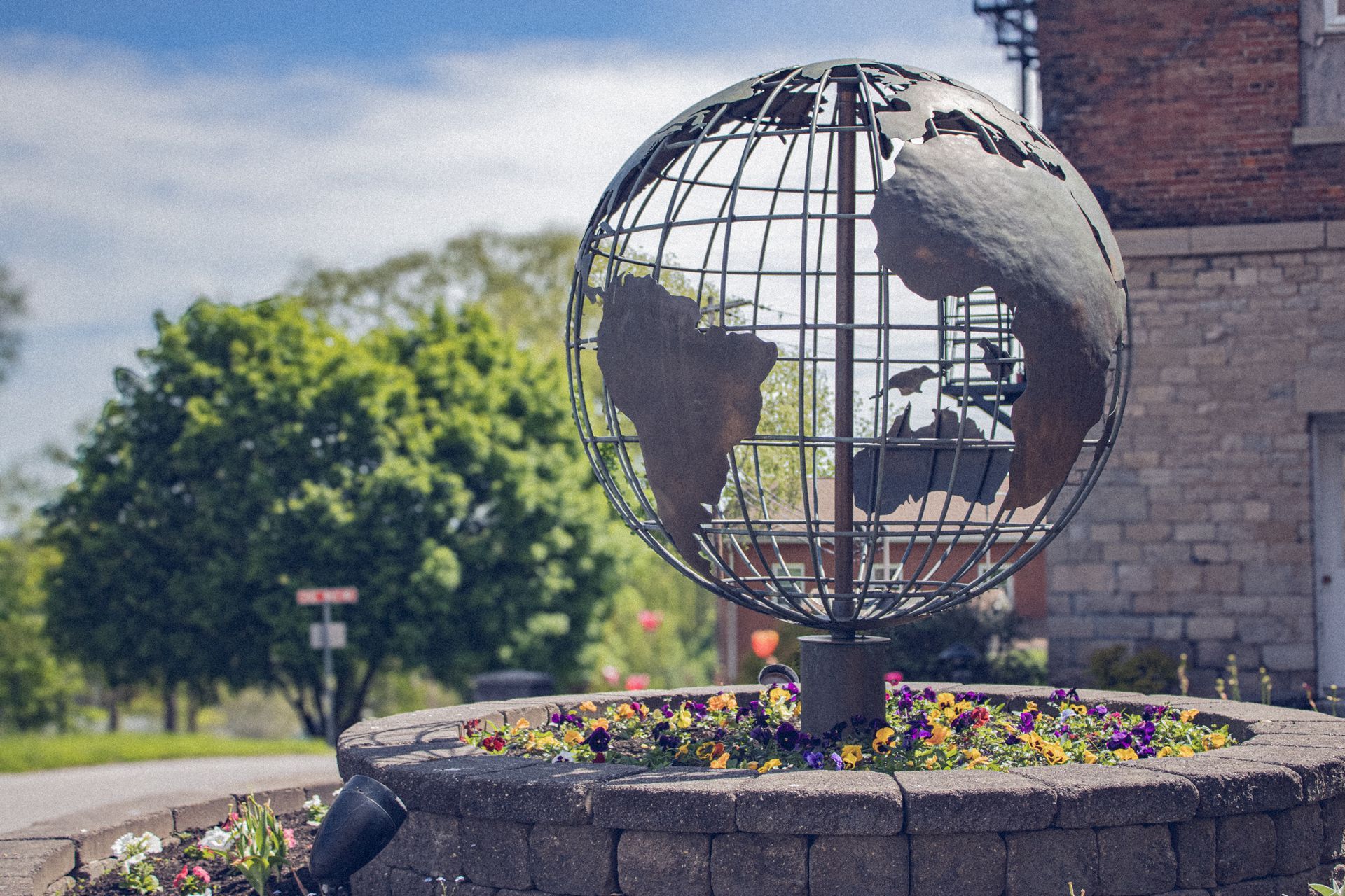 the Elim globe sculpture surrounded by flowers 