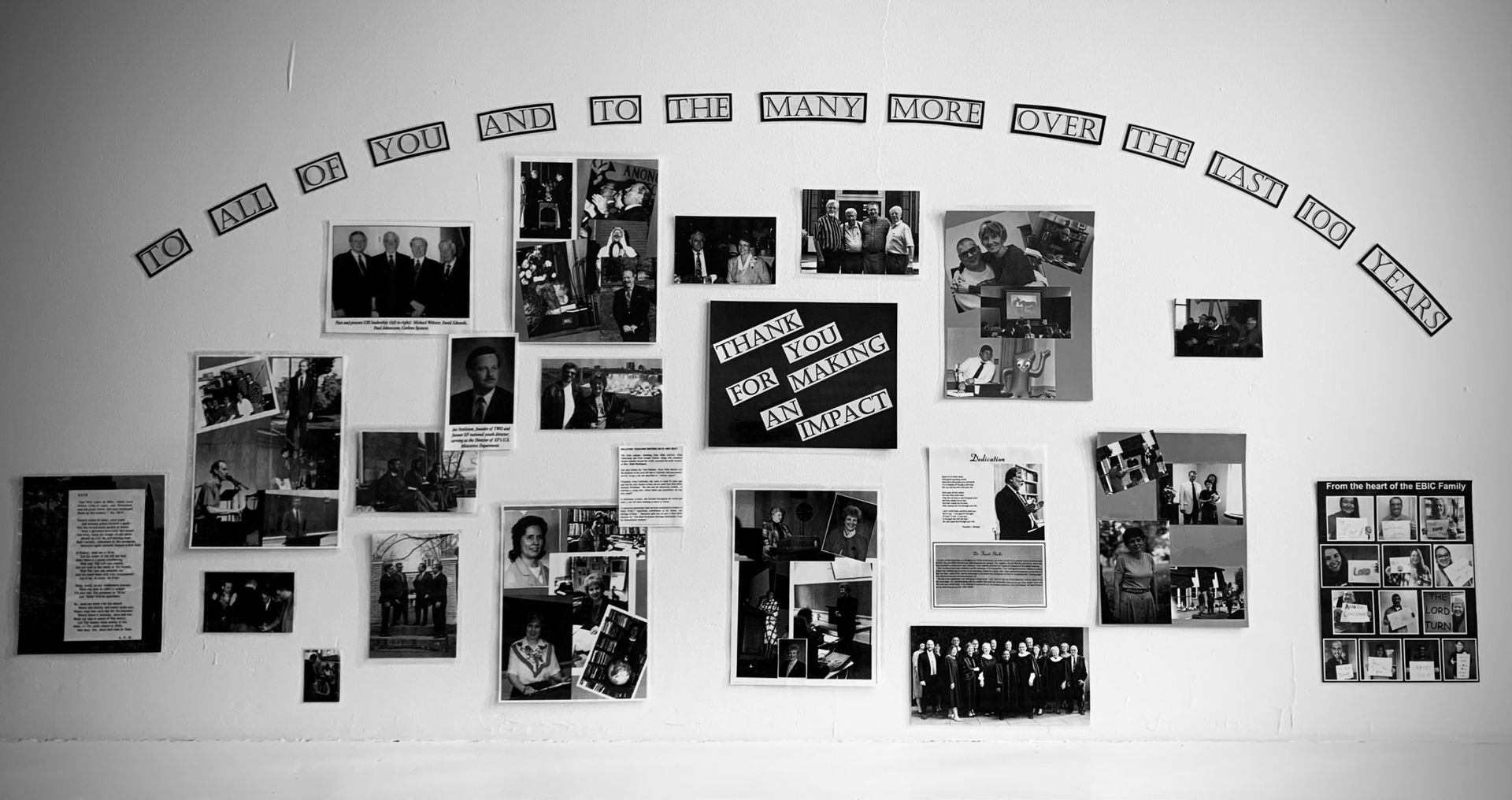 A wall display featuring black and white photographs and text in an arch formation. The photos depict people and events.