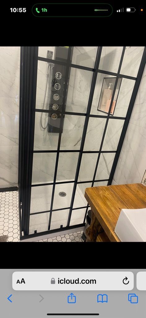 A bathroom with a black shower door and a sink.