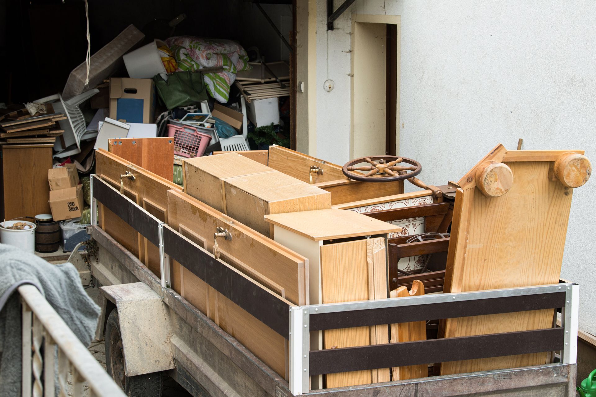 Wooden furniture pieces loaded onto a truck, with a cluttered background.