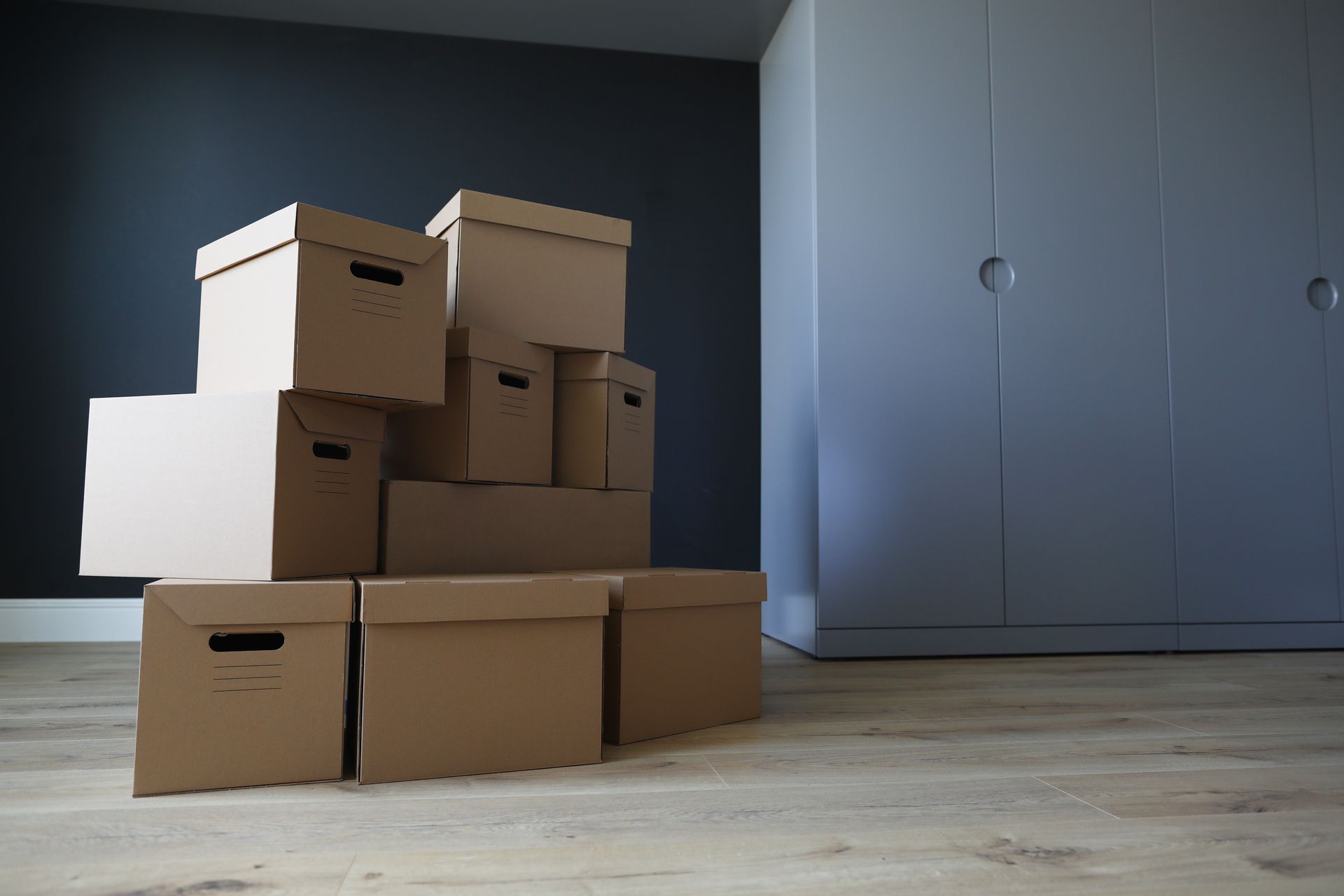 Stack of cardboard moving boxes in a room; a large closet is in the background.