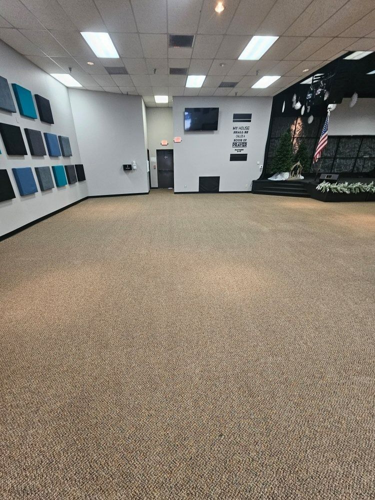 Empty room with carpet and a wall display of colored squares. TV and exit door visible.