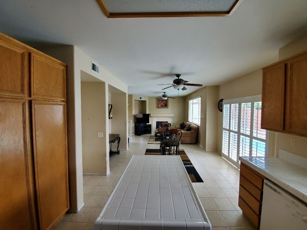 Kitchen view into living room with wood cabinets, tiled floors, and a sliding glass door.