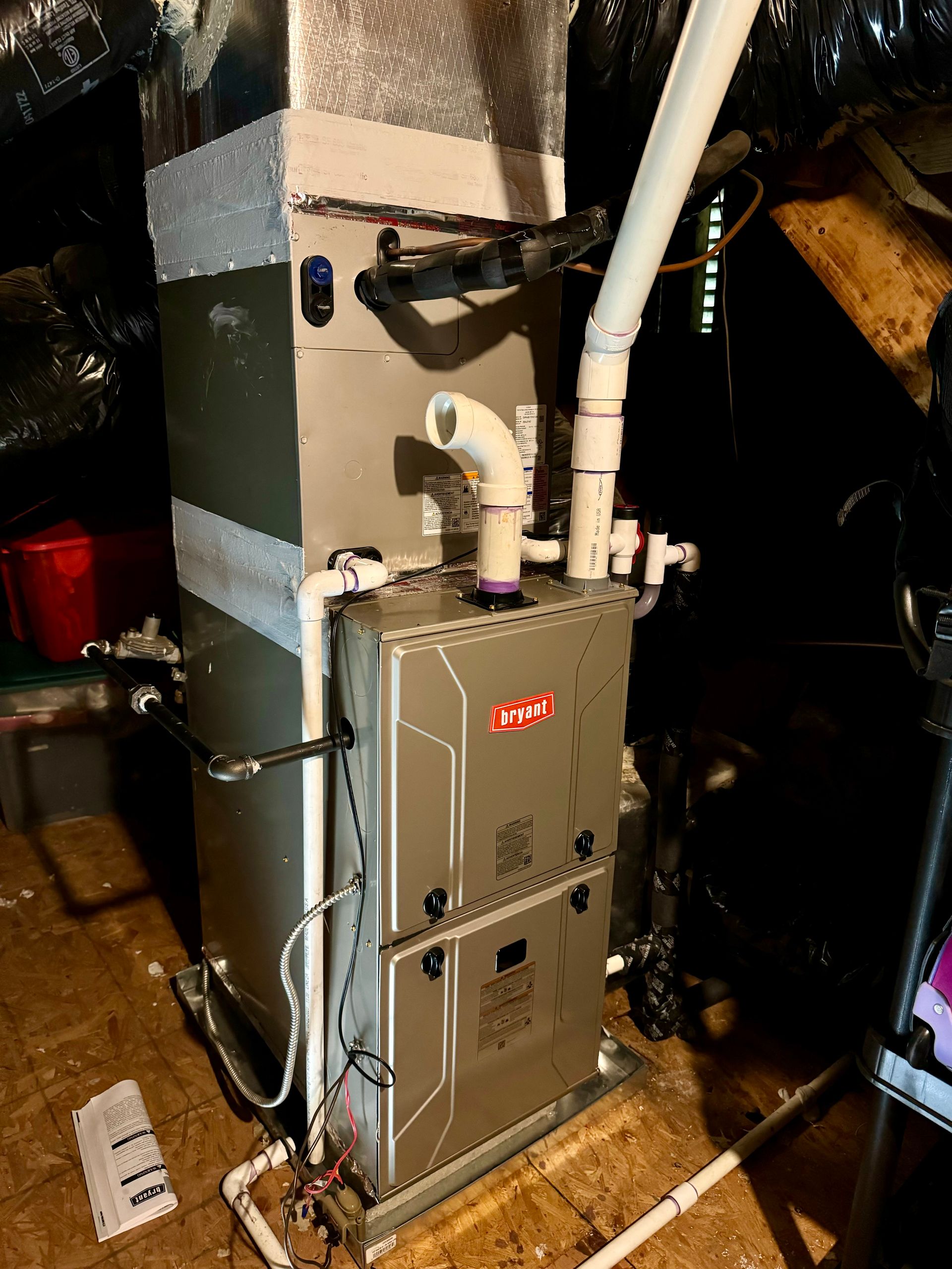 A furnace is sitting on the floor in a basement.