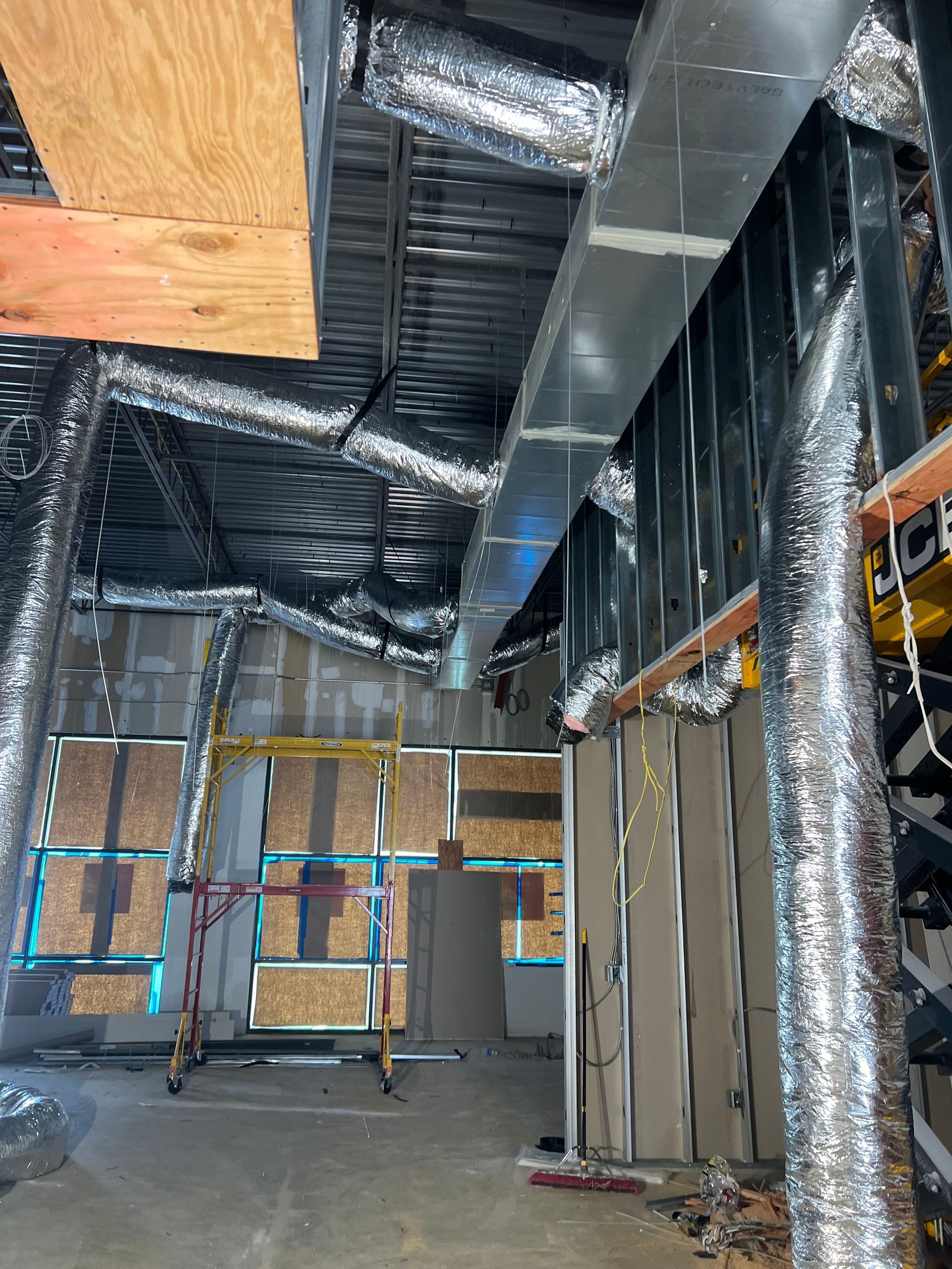 A building under construction with a lot of pipes coming out of the ceiling.