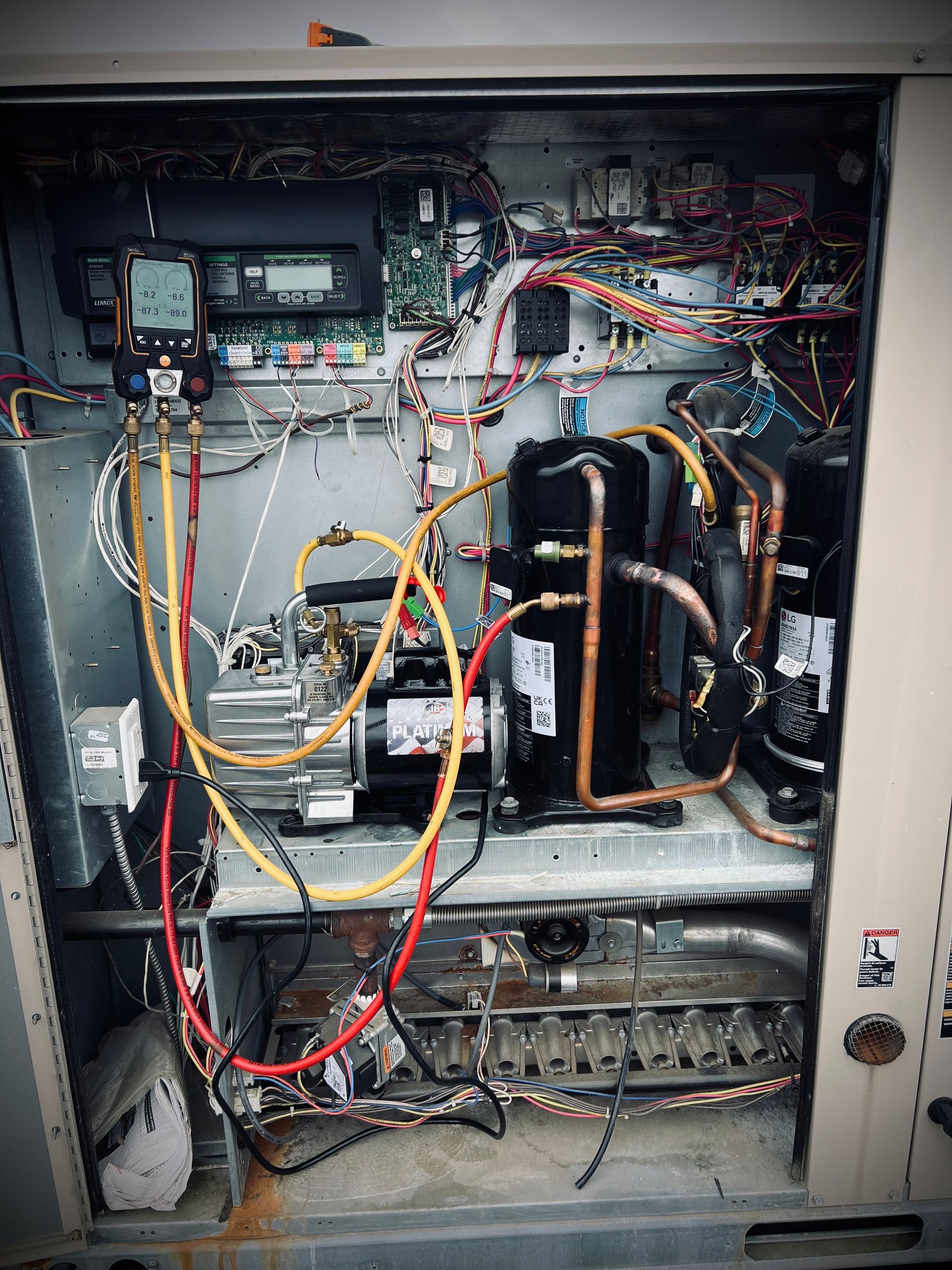 The inside of a refrigerator with a lot of wires coming out of it.