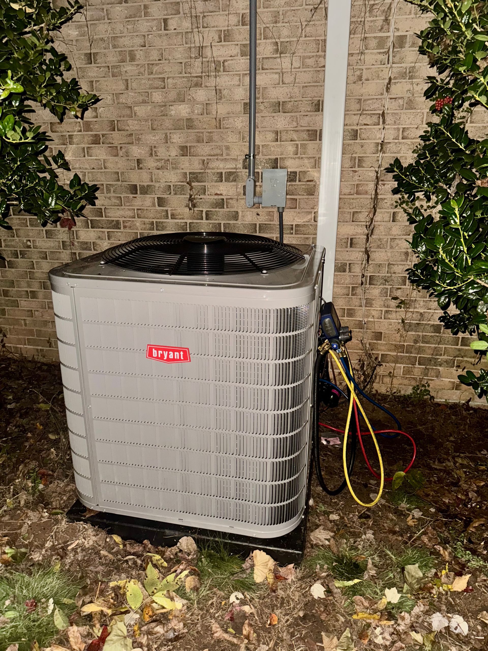 A large air conditioner is sitting in front of a brick wall.