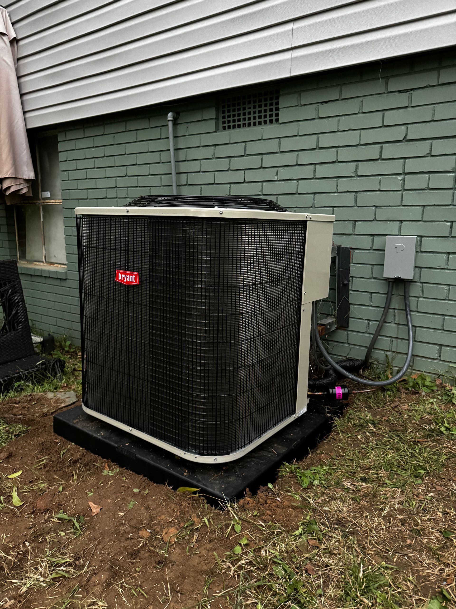 An air conditioner is sitting outside of a brick building.