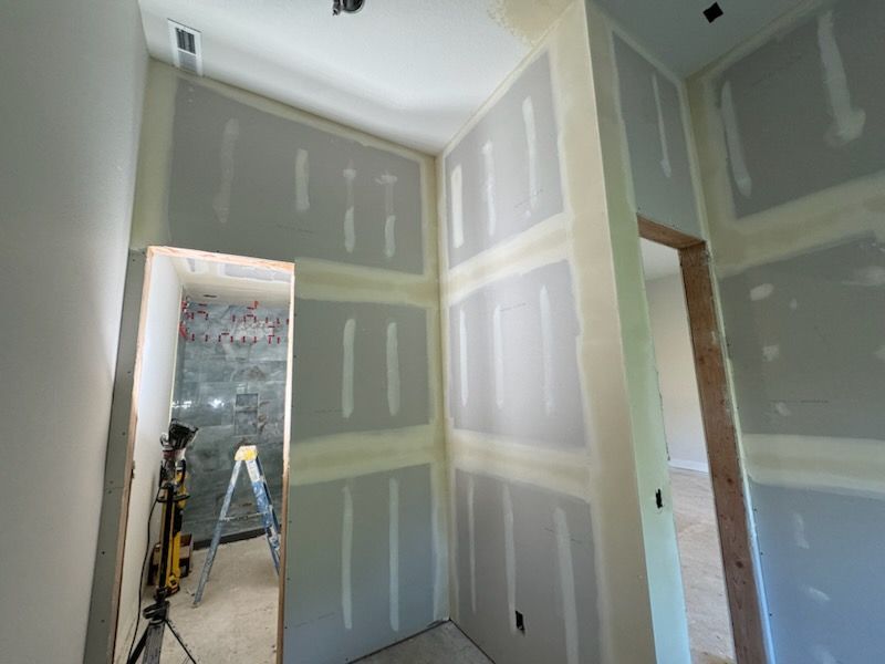 Interior view of a hallway with drywall, partially taped and finished, doorway openings.