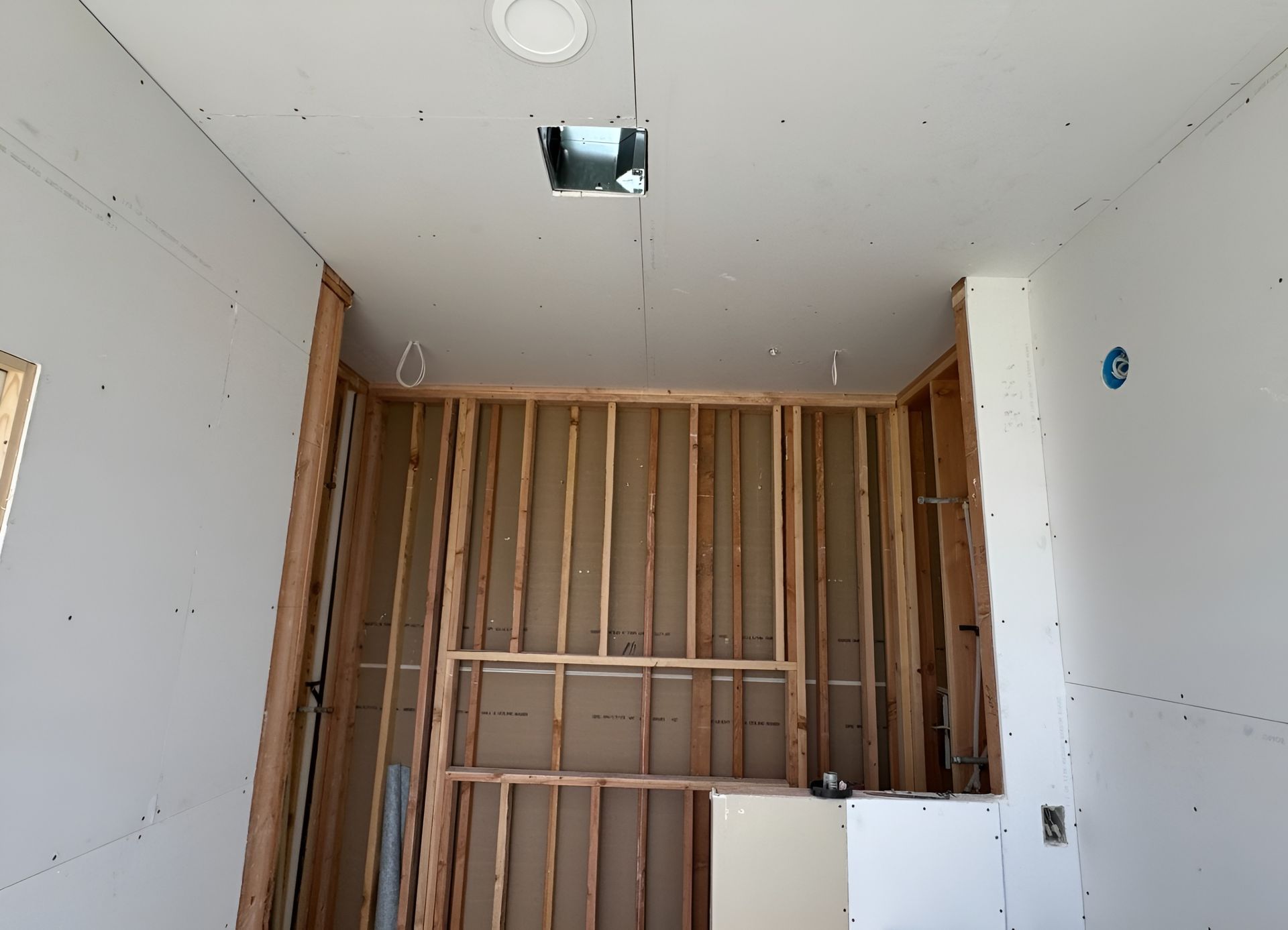 Bathroom under construction with exposed wooden studs, drywall partially installed.