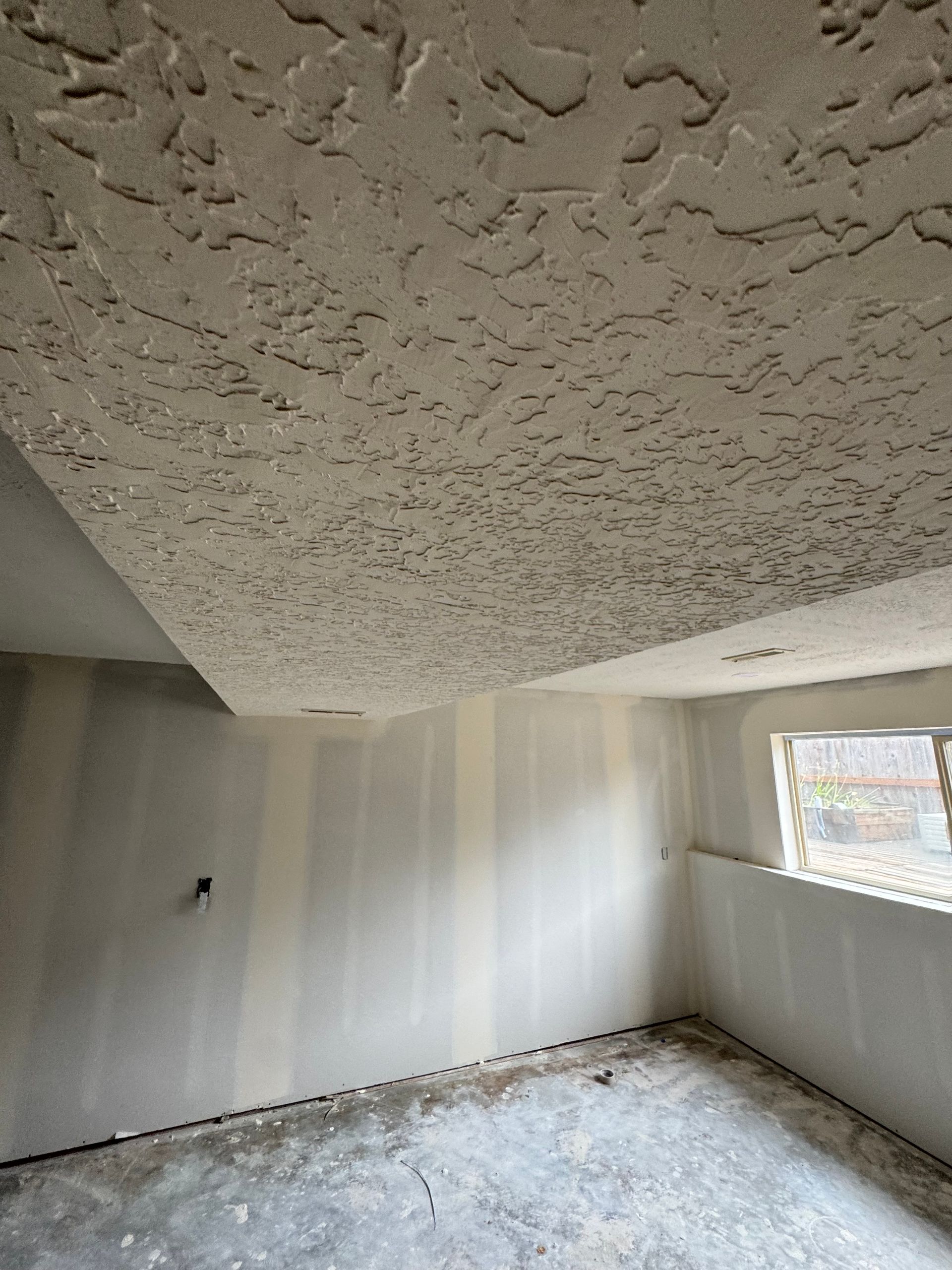 Hands using a putty knife to apply spackle to a wall, filling a damaged area.