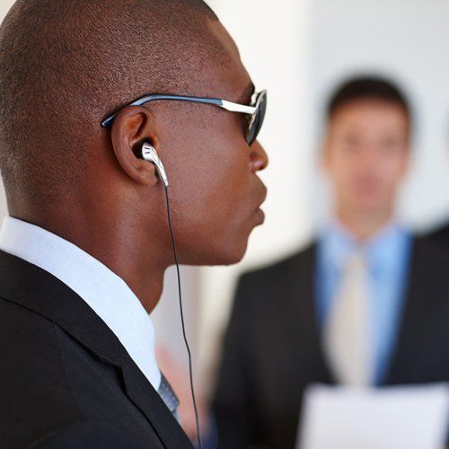 Shot of a serious bodyguard protecting his client who is giving a presentation