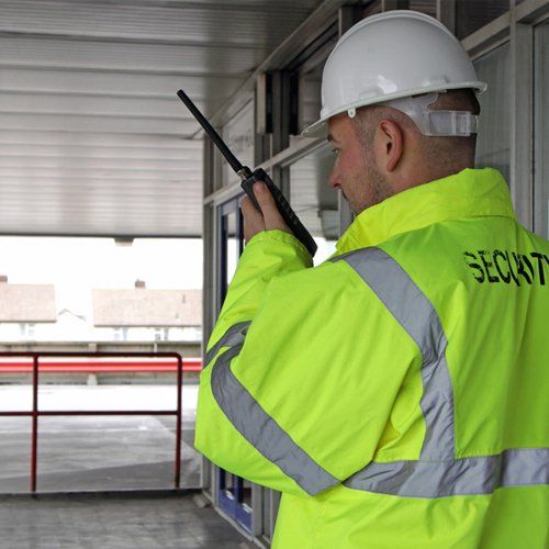 A security man reporting to HQ on a walkie talkie after checking the security of a entrance to a office block.