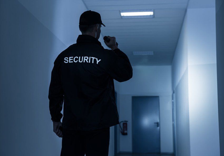 Rear view of security guard with flashlight in building corridor