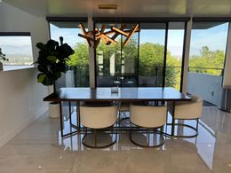 A dining room with a table and chairs and a large window.
