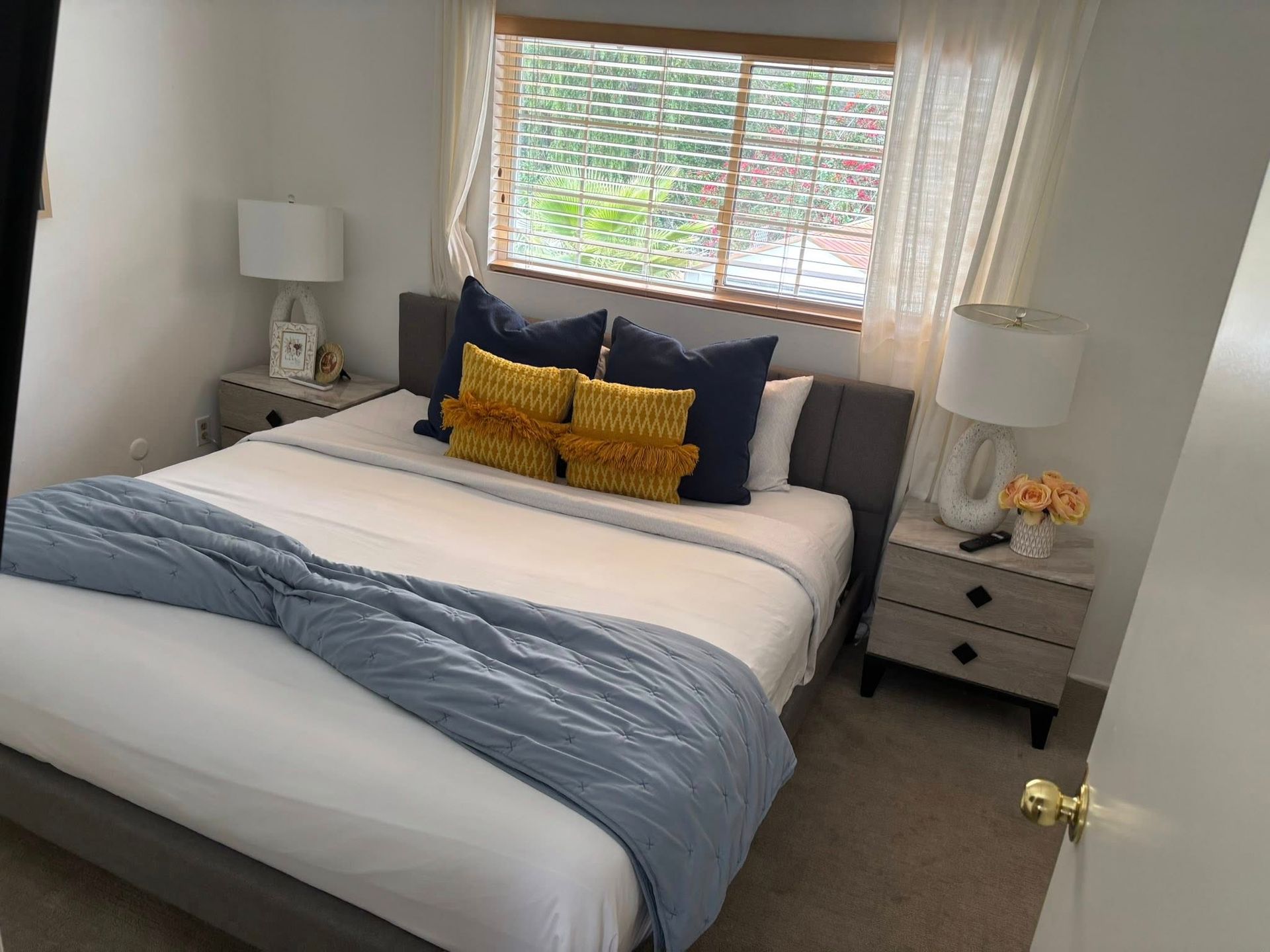 A bedroom with a bed , nightstands , lamps and a window.