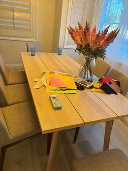 A dining room table with a vase of flowers and a remote control on it.