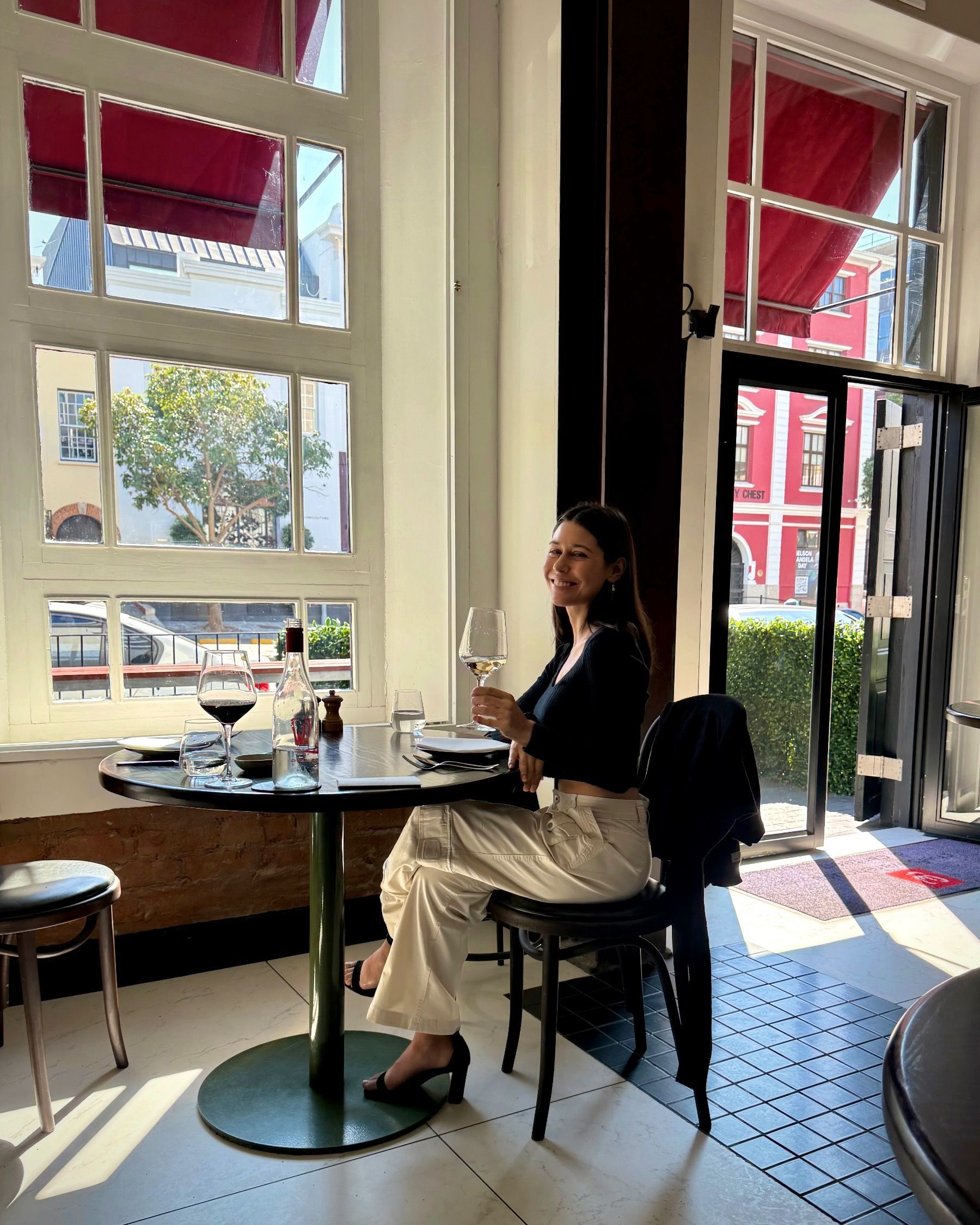 Paige seated smiling inside Chefs Warehouse & Canteen Cape Town’s warm brick dining space