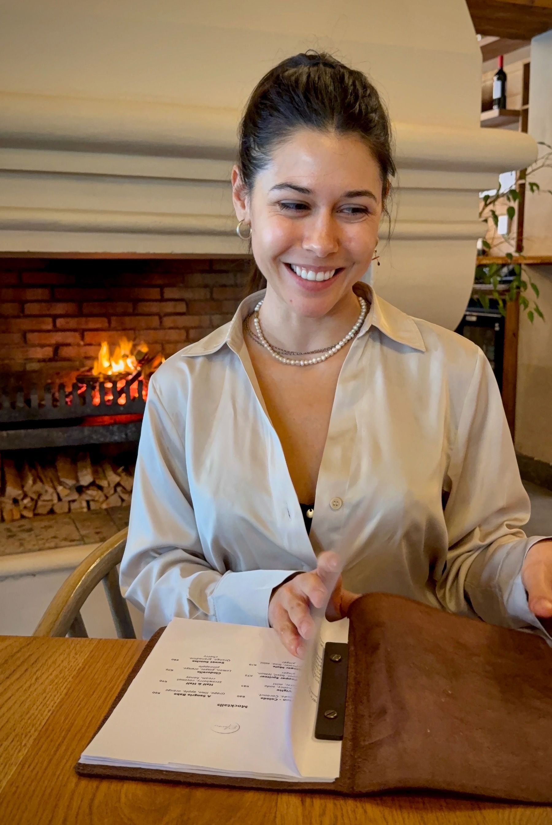 Paige browsing Eleven Franschhoek tasting menu by the fireplace
