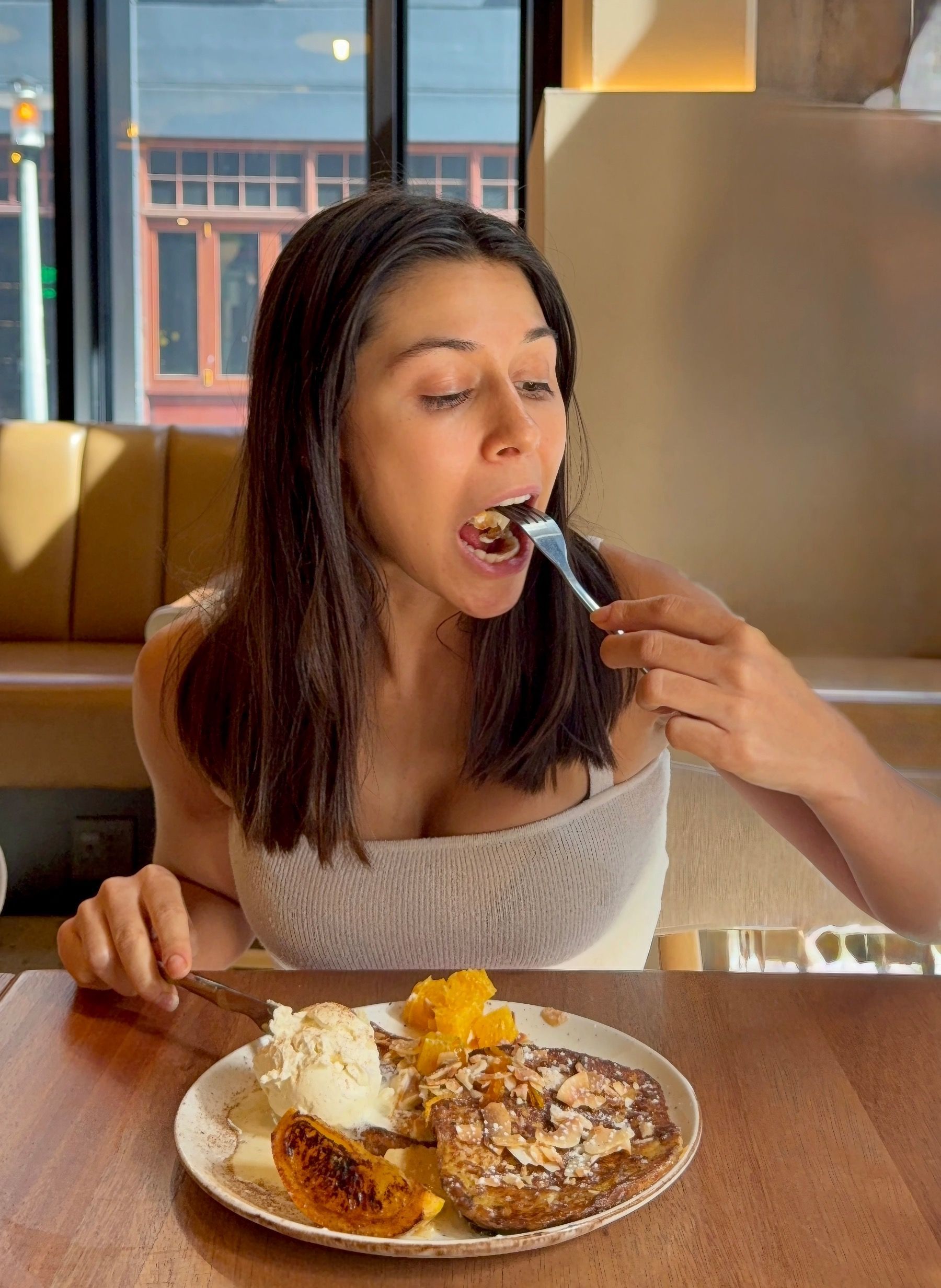 Paige taking a bite of Florentin toast inside warm, modern restaurant interior
