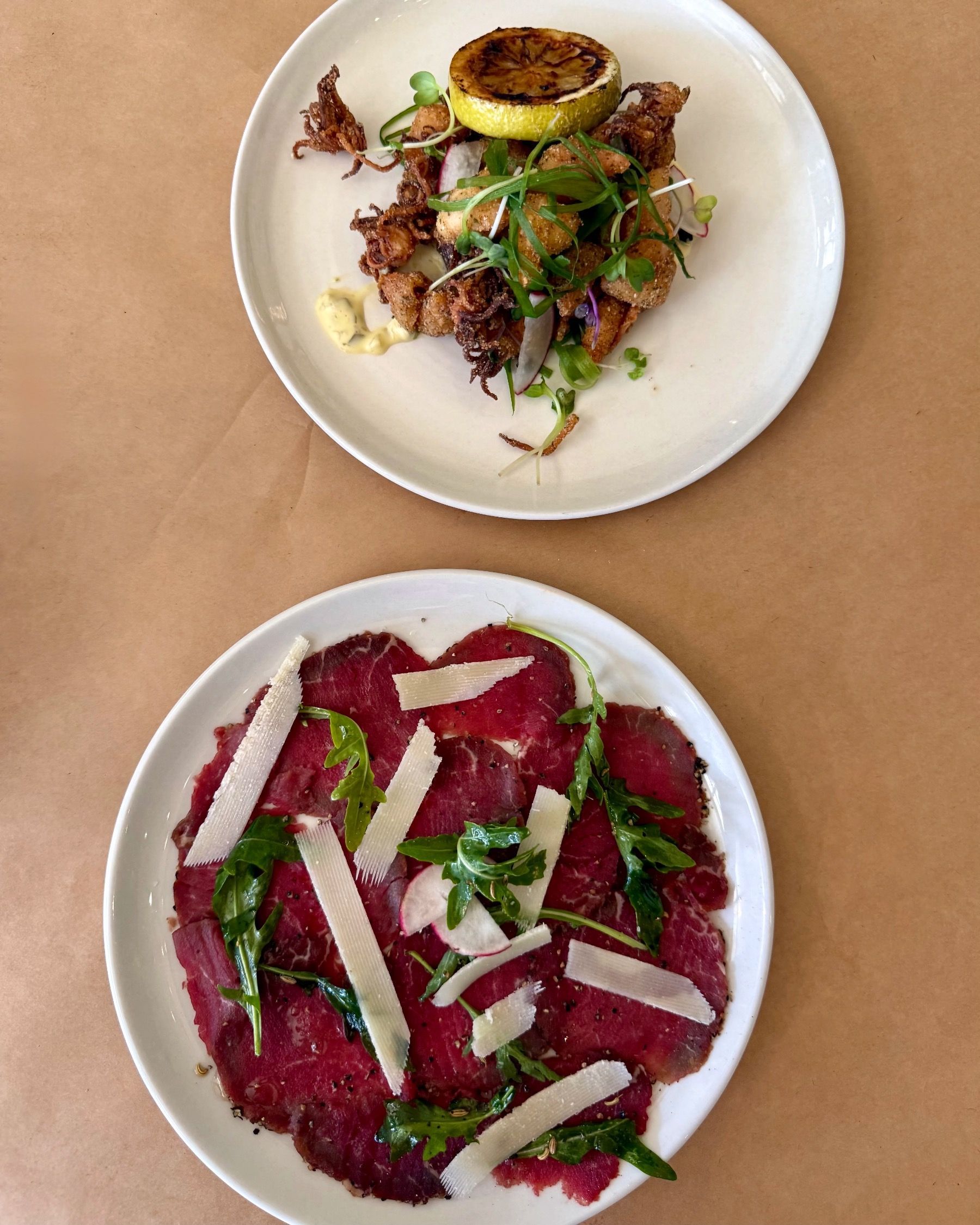 Beef fillet carpaccio with parmesan and fennel alongside salt and pepper calamari with lemon aioli at HQ Steakhouse