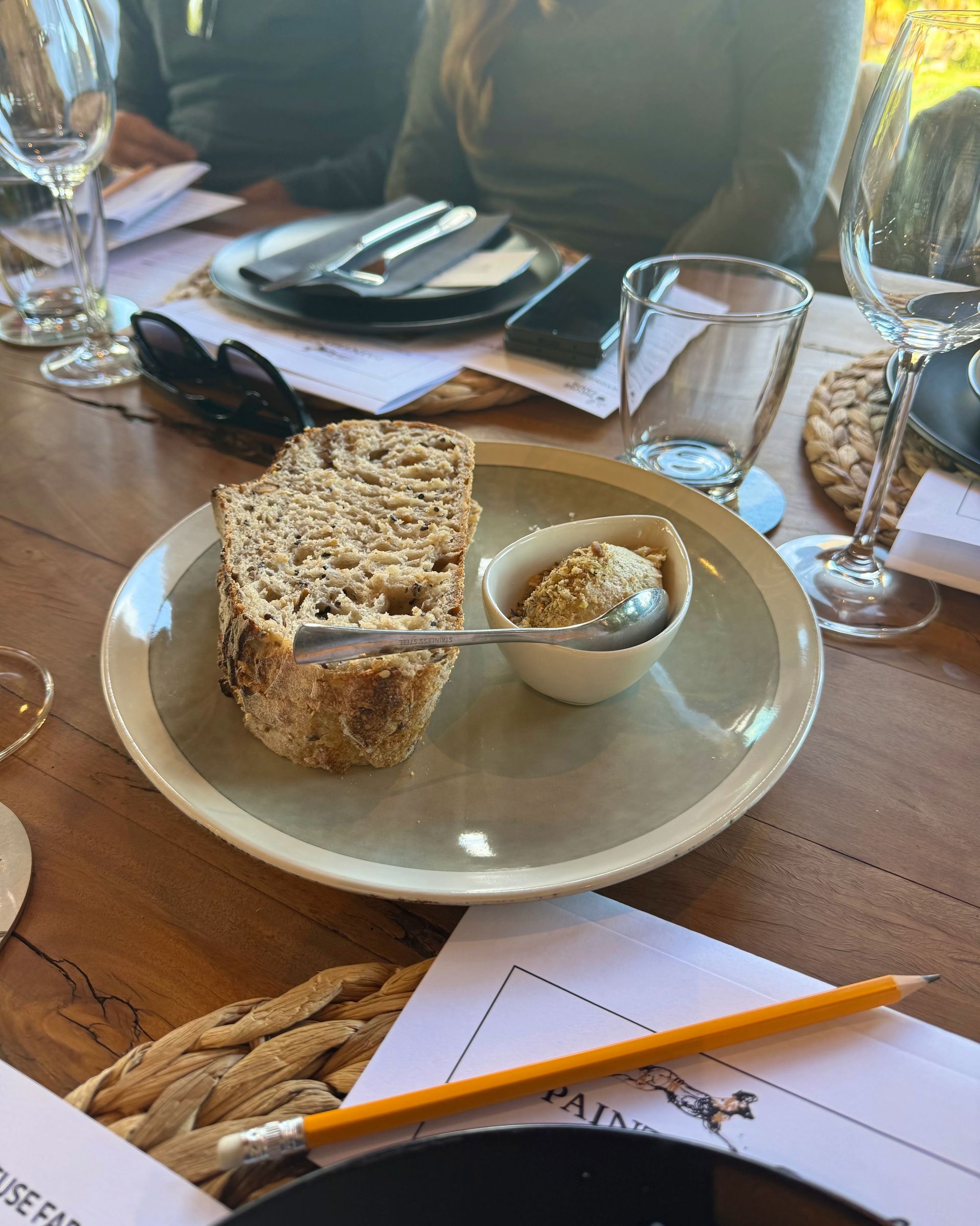Small appetizer on a black plate with greens, a knife, and a water glass.