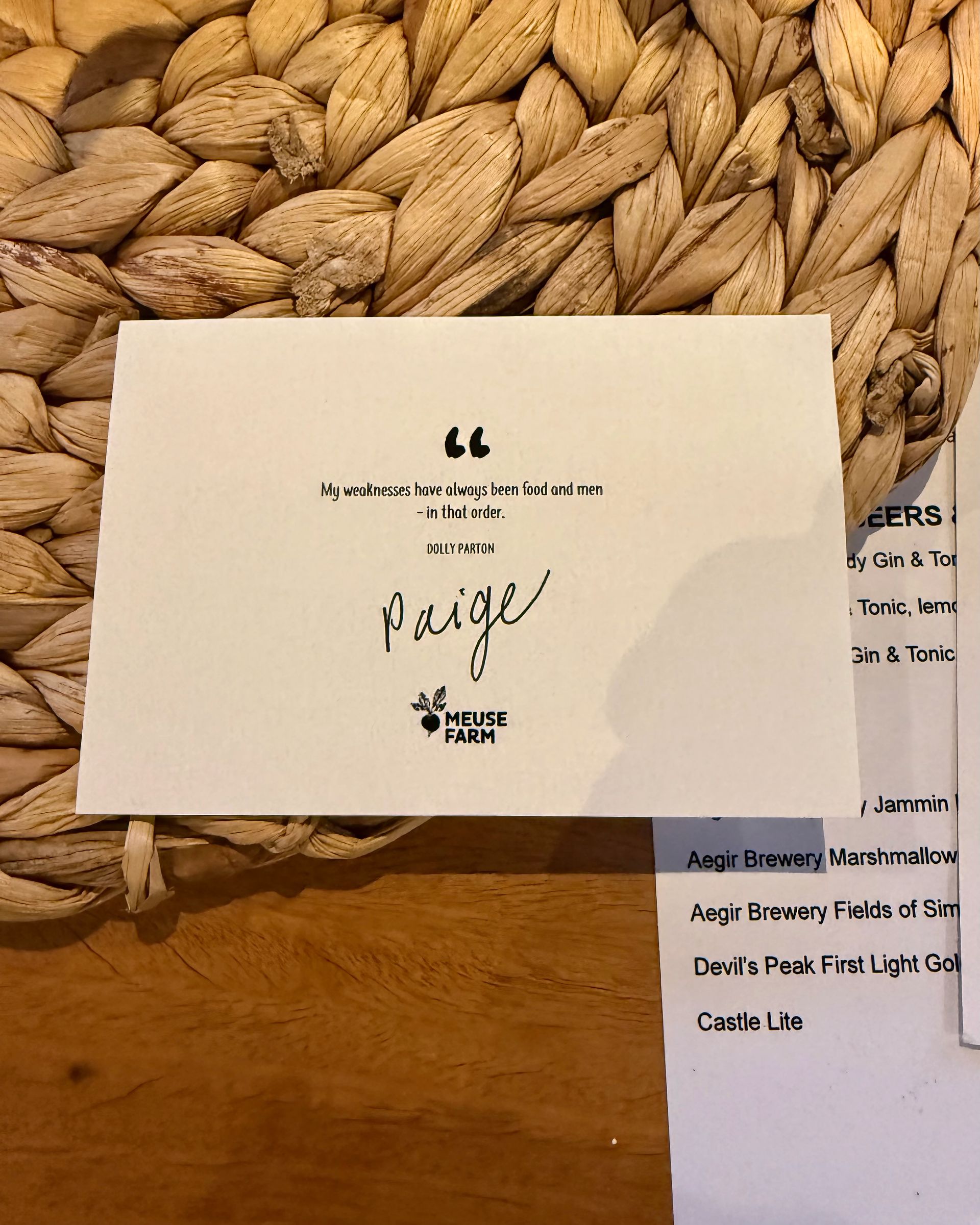 White card with handwritten text, a signature, and a logo. Woven background.
