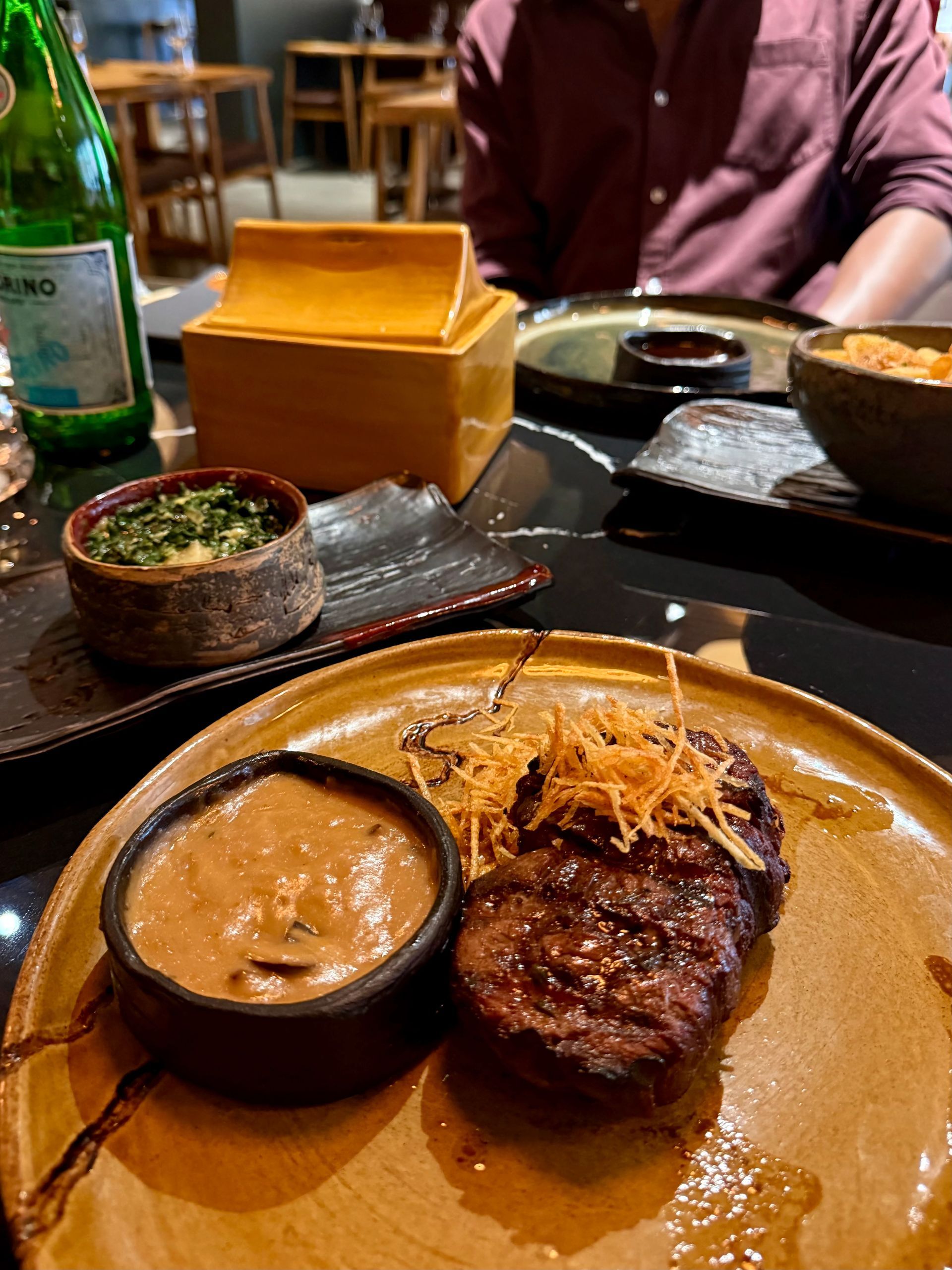 Dessert plate with green-dusted cake, ice cream, and jellies. Person sits at a table in a restaurant setting.