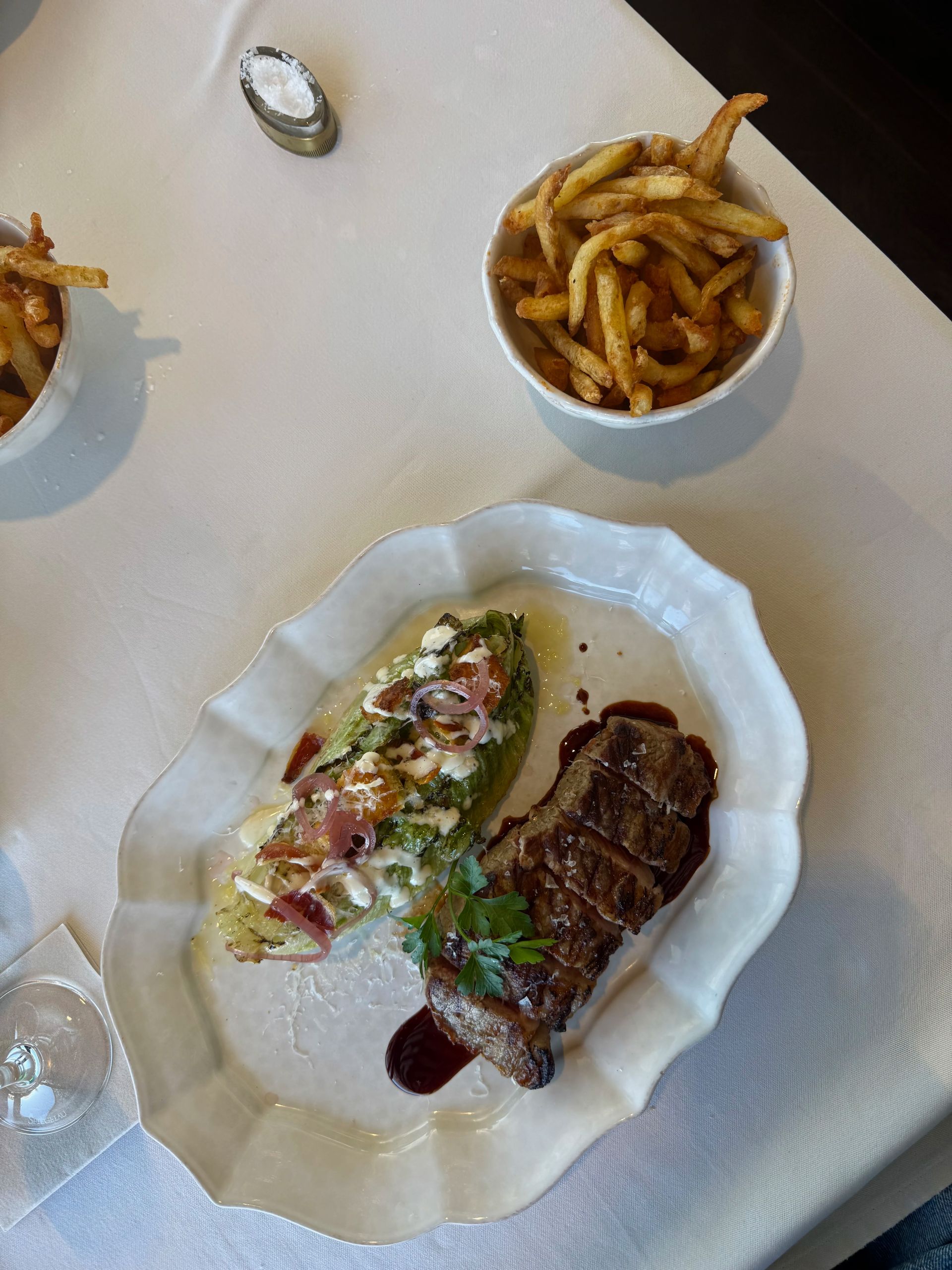 Steak with zucchini side and fries in a fine dining setting, white table cloth.
