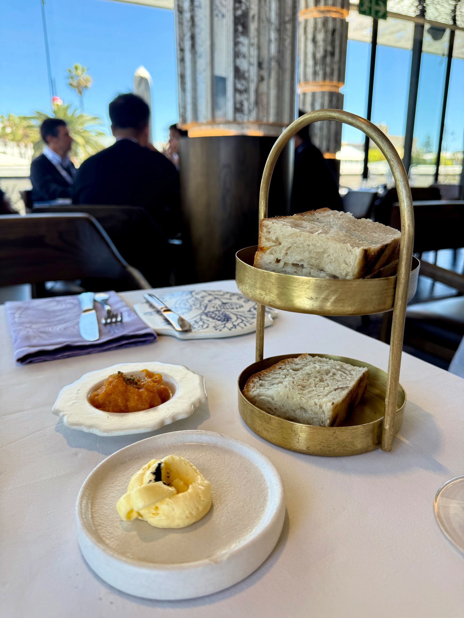 Bread service with butter and jam on a restaurant table.