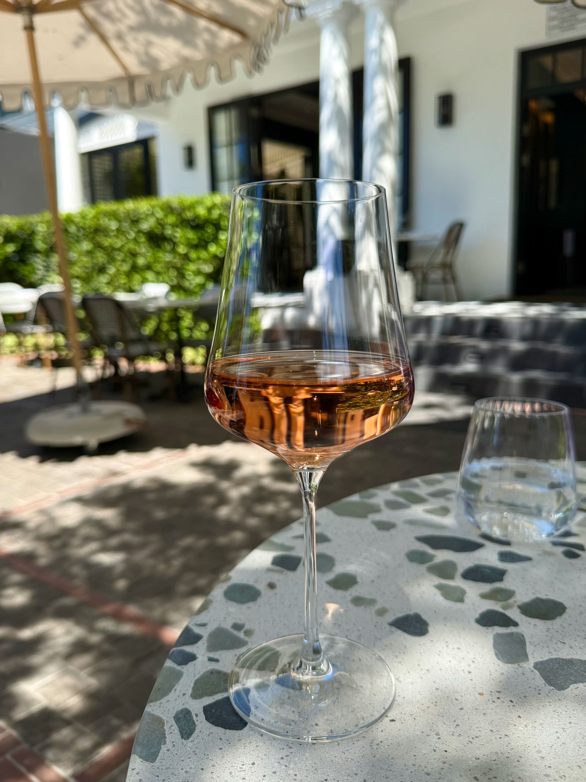 Glass of rosé wine on a table outside a restaurant, sunny day.