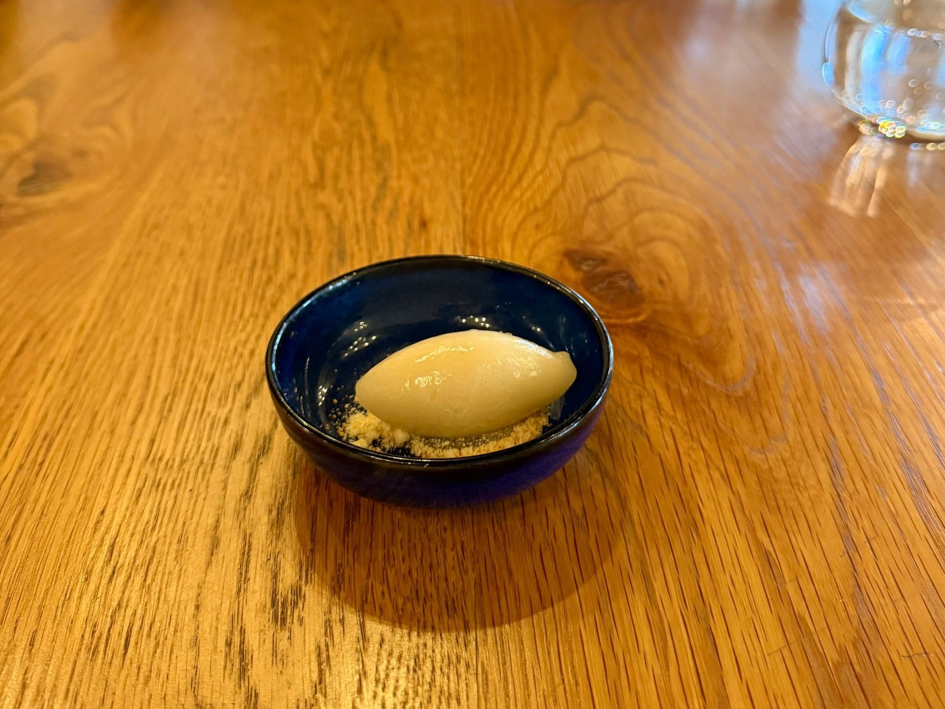 Dessert in a blue bowl on a wooden table: sorbet with crumbly topping.