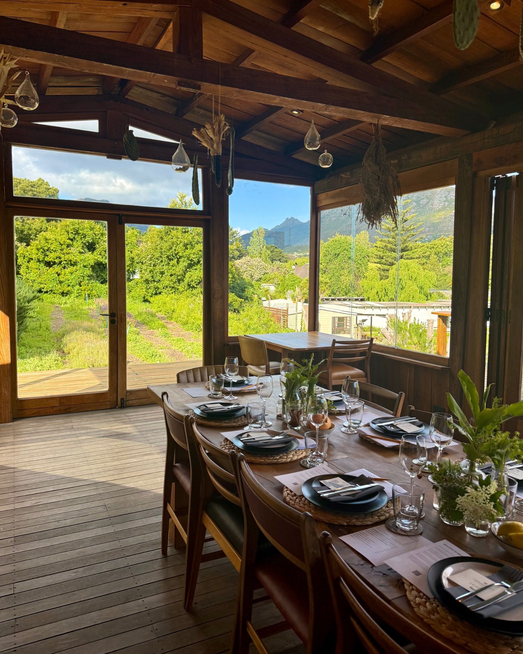 Table overlooking Meuse Farm vegetable rows and mountain views during Painted Wolf wine pairing event
