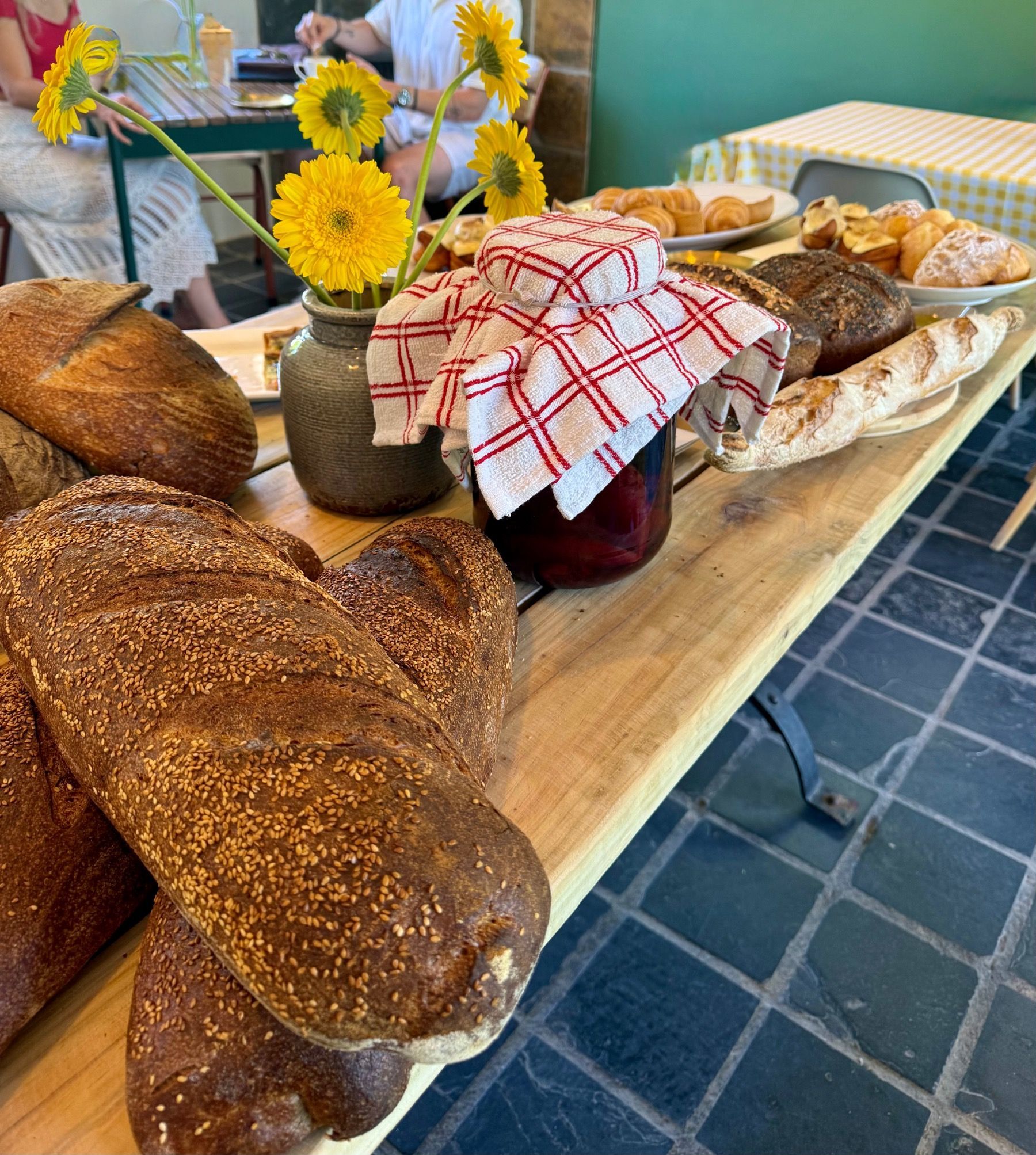 Rustic sourdough loaves, pastries and baked goods displayed on a wooden table at Motherdough bakery in Jonkershoek