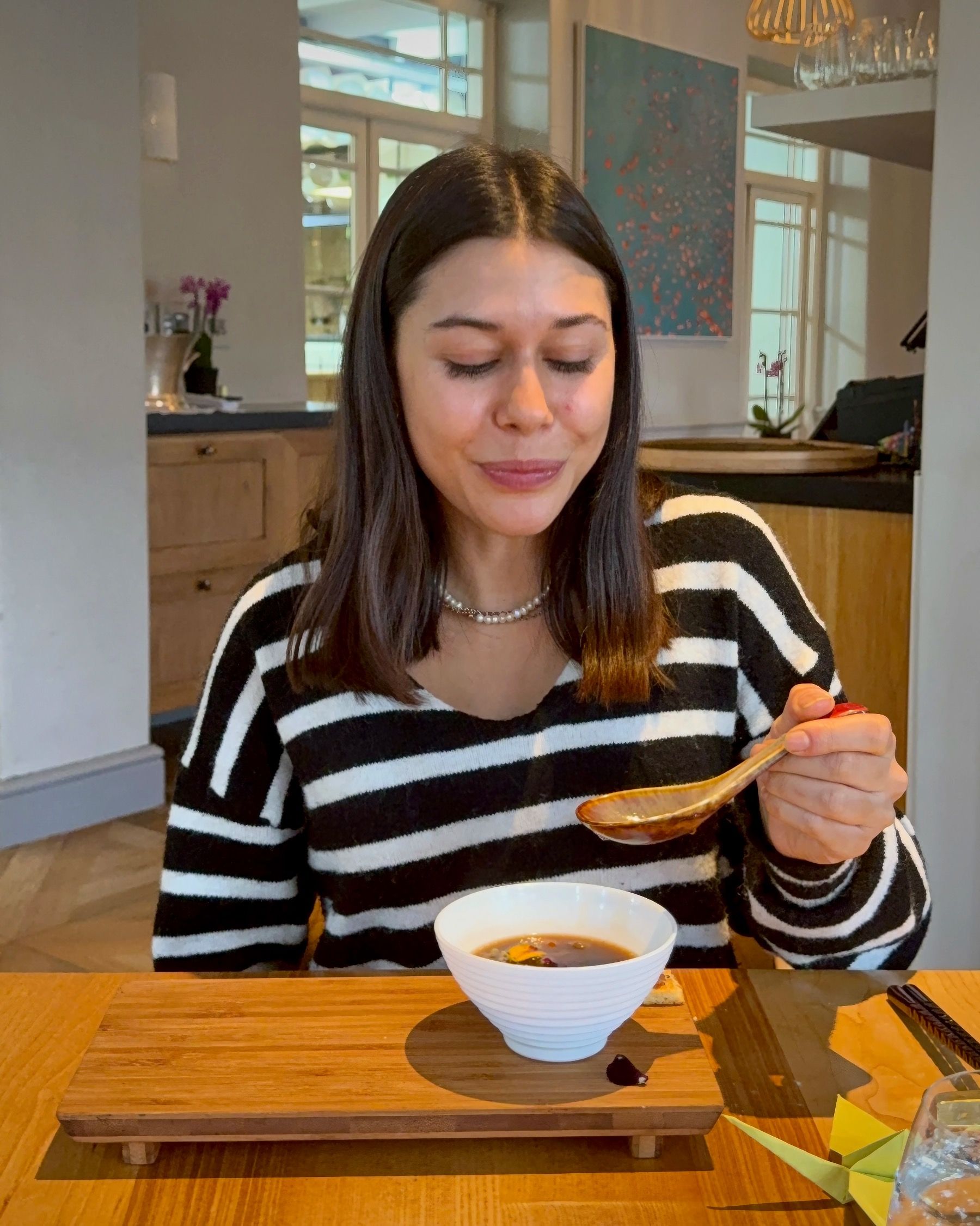 Paige tasting rich beef bone broth course at Oku.