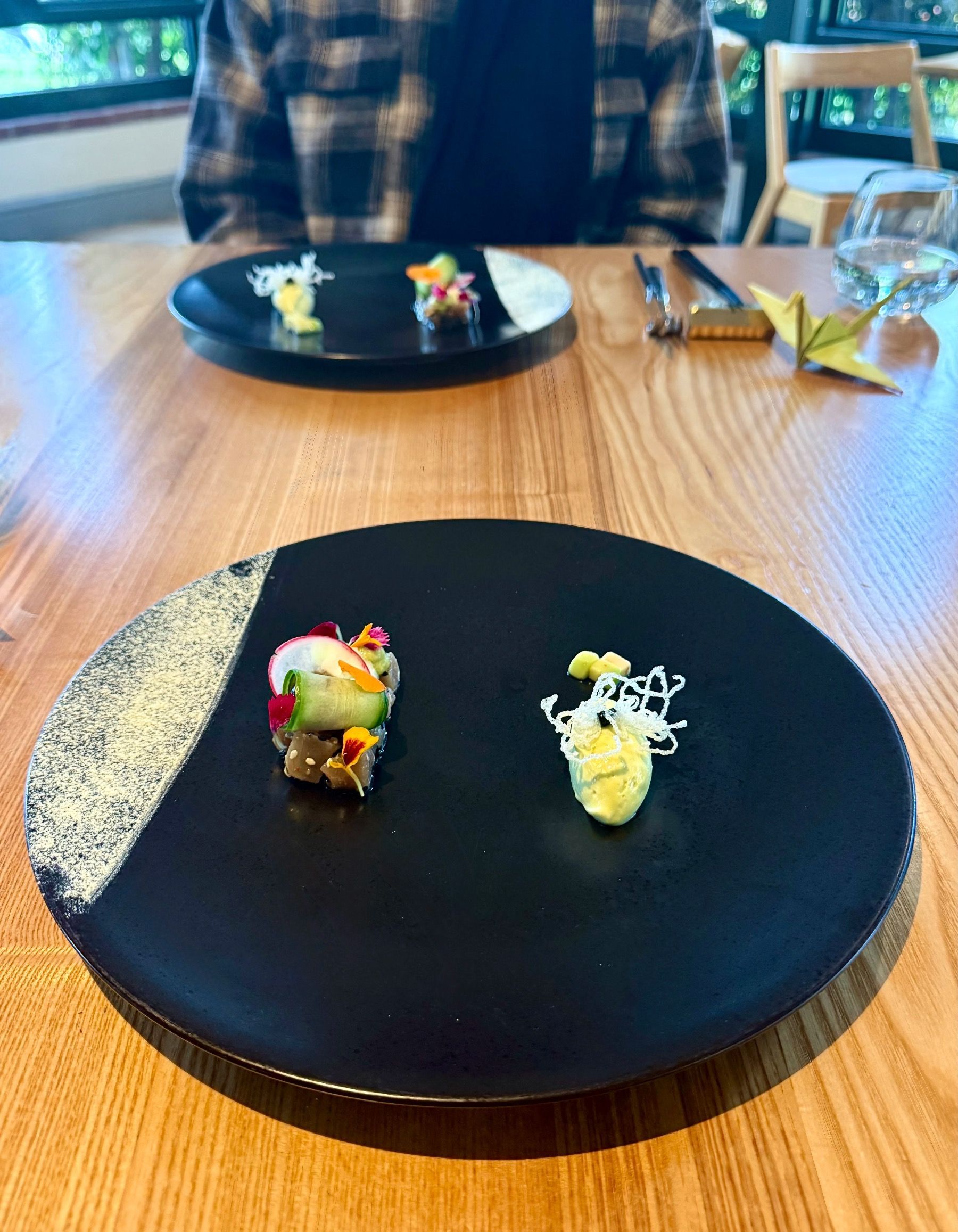 Tuna tataki with wasabi mousse and delicate garnish on black plate.