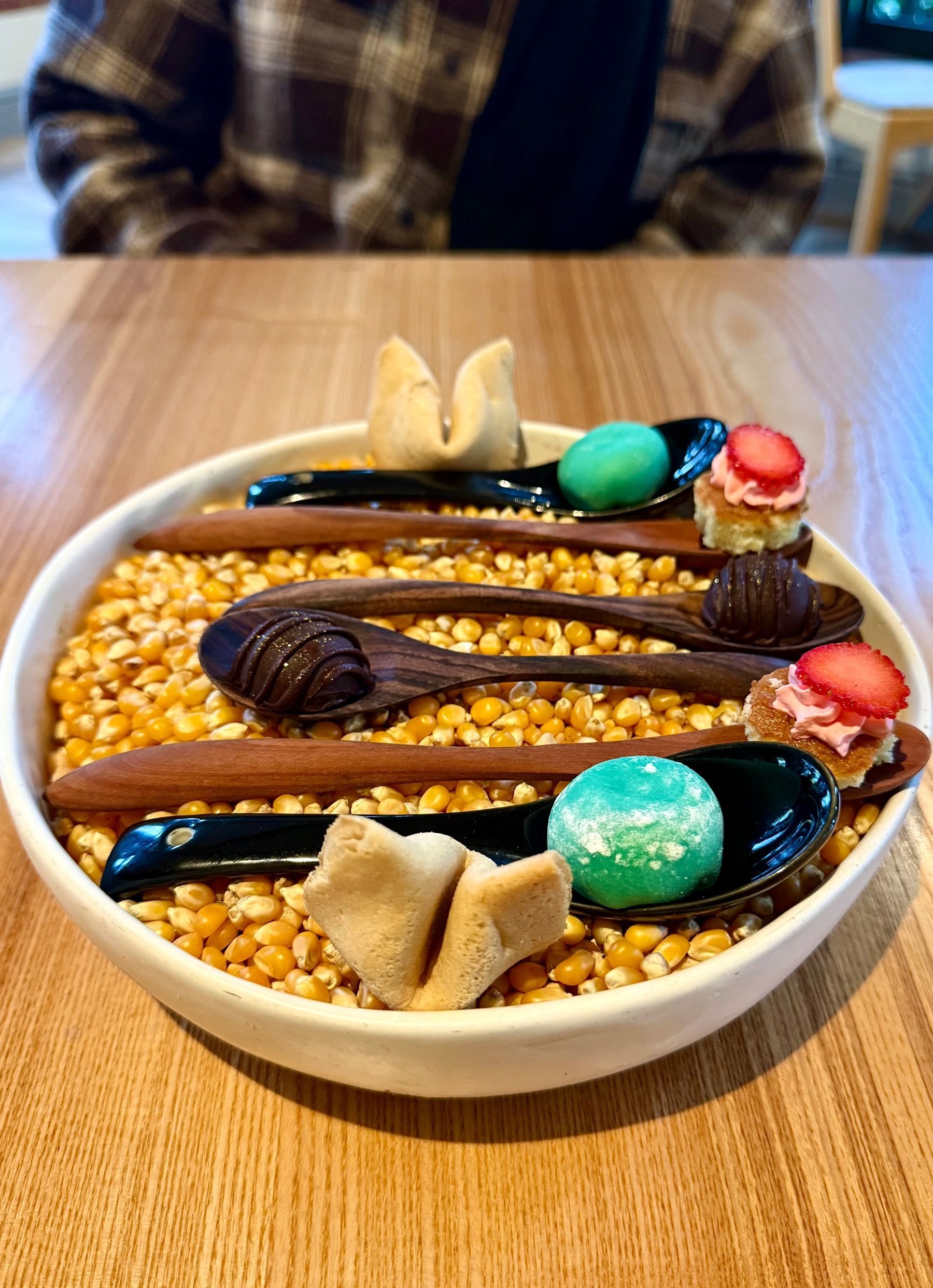A bowl of corn kernels with Selection of petit fours including truffle and mochi 
