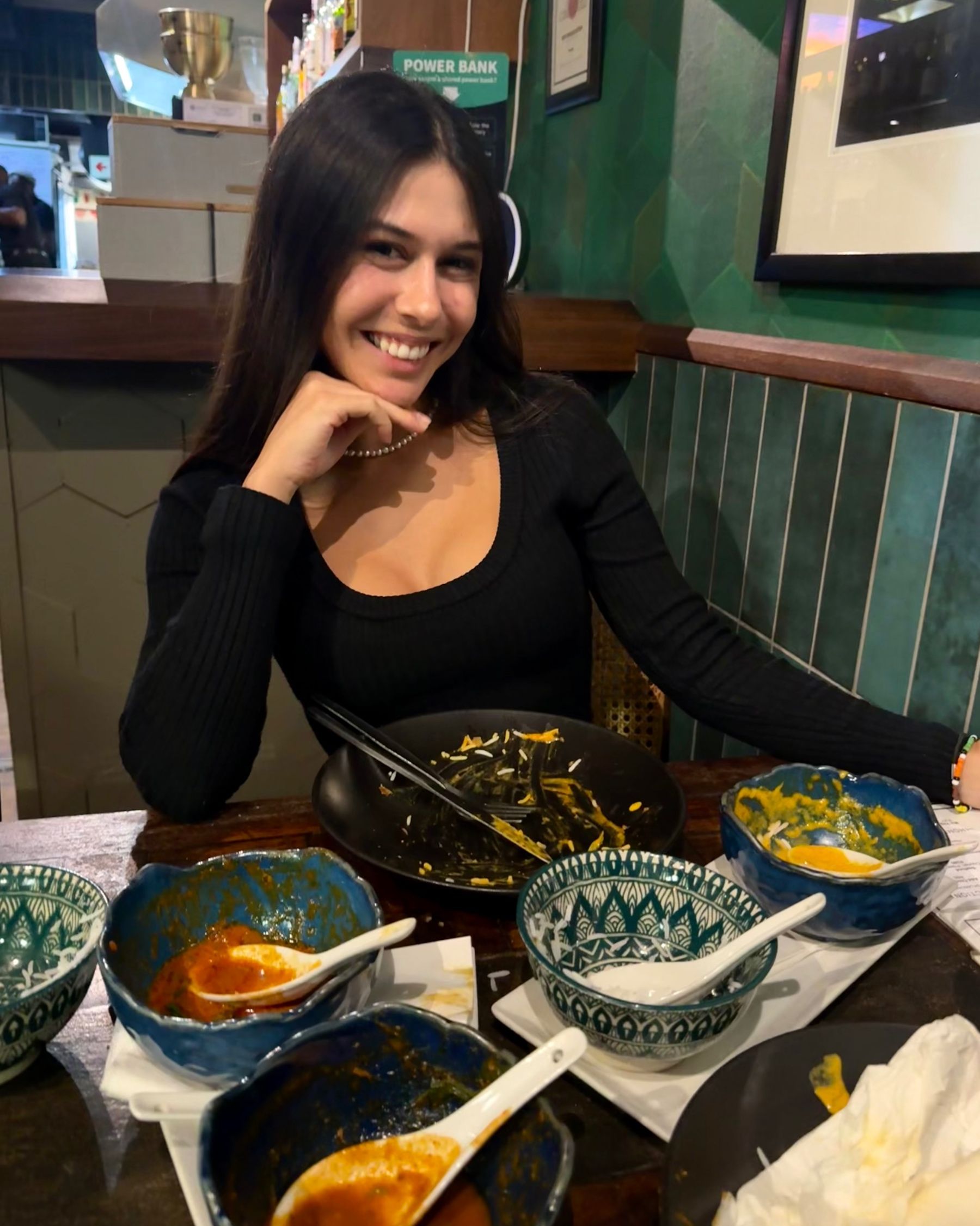 Paige is smiling beside empty curry plates at Sundoo Sea Point