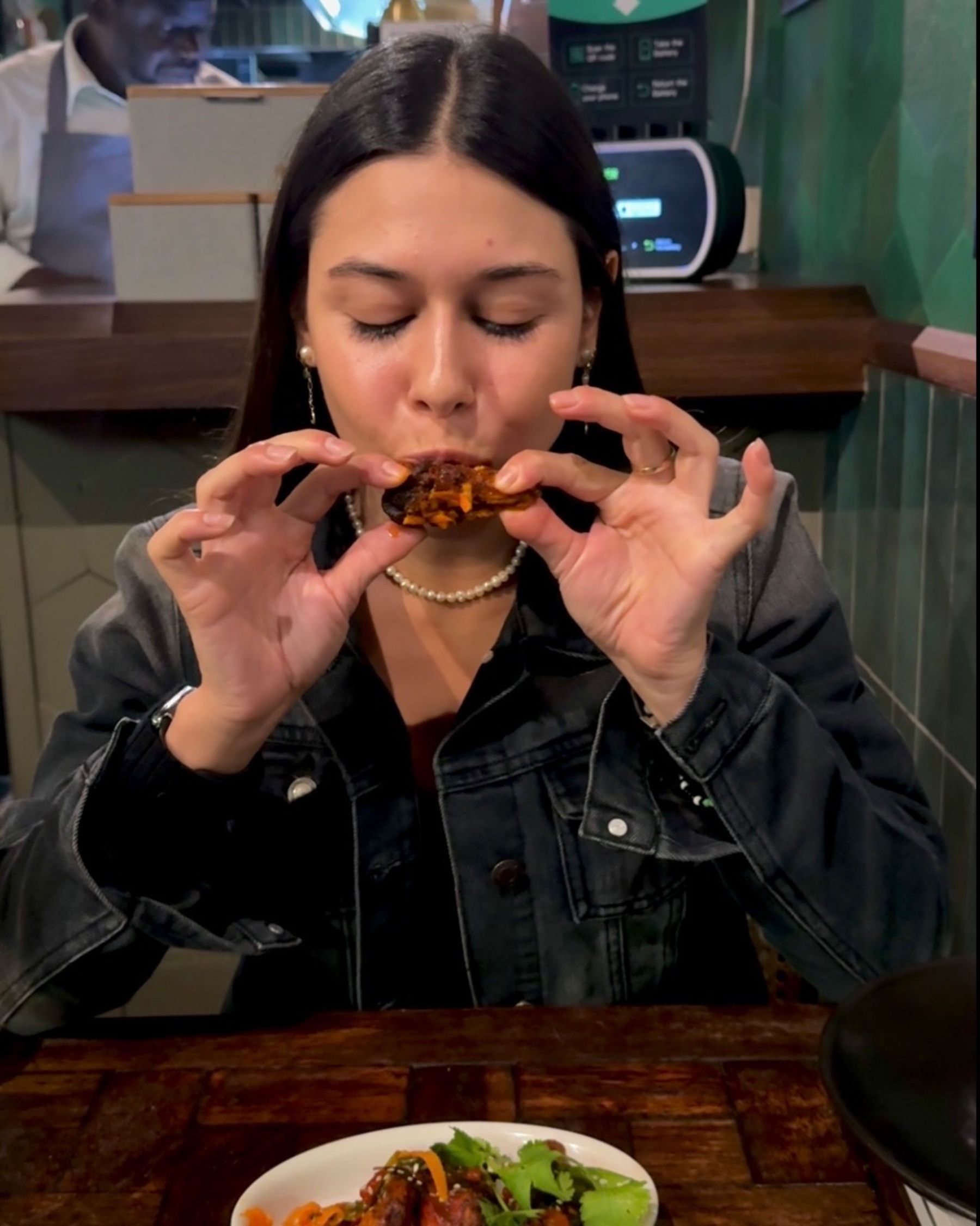 Paige is eating tandoori chicken wings at Sundoo Sea Point