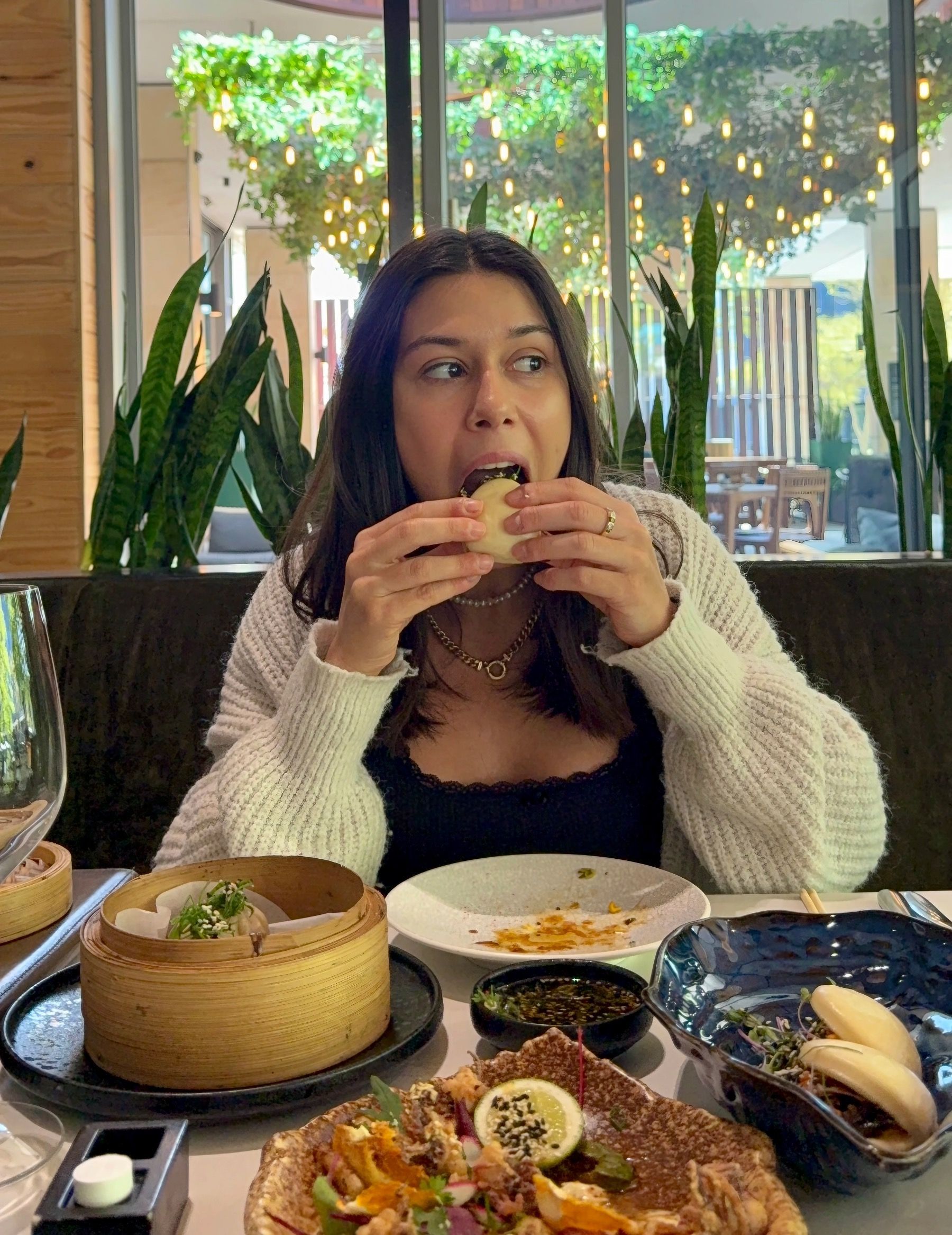 Paige is biting into a soft beef bao bun at Urban Umami, filled with savoury Asian-inspired flavours
