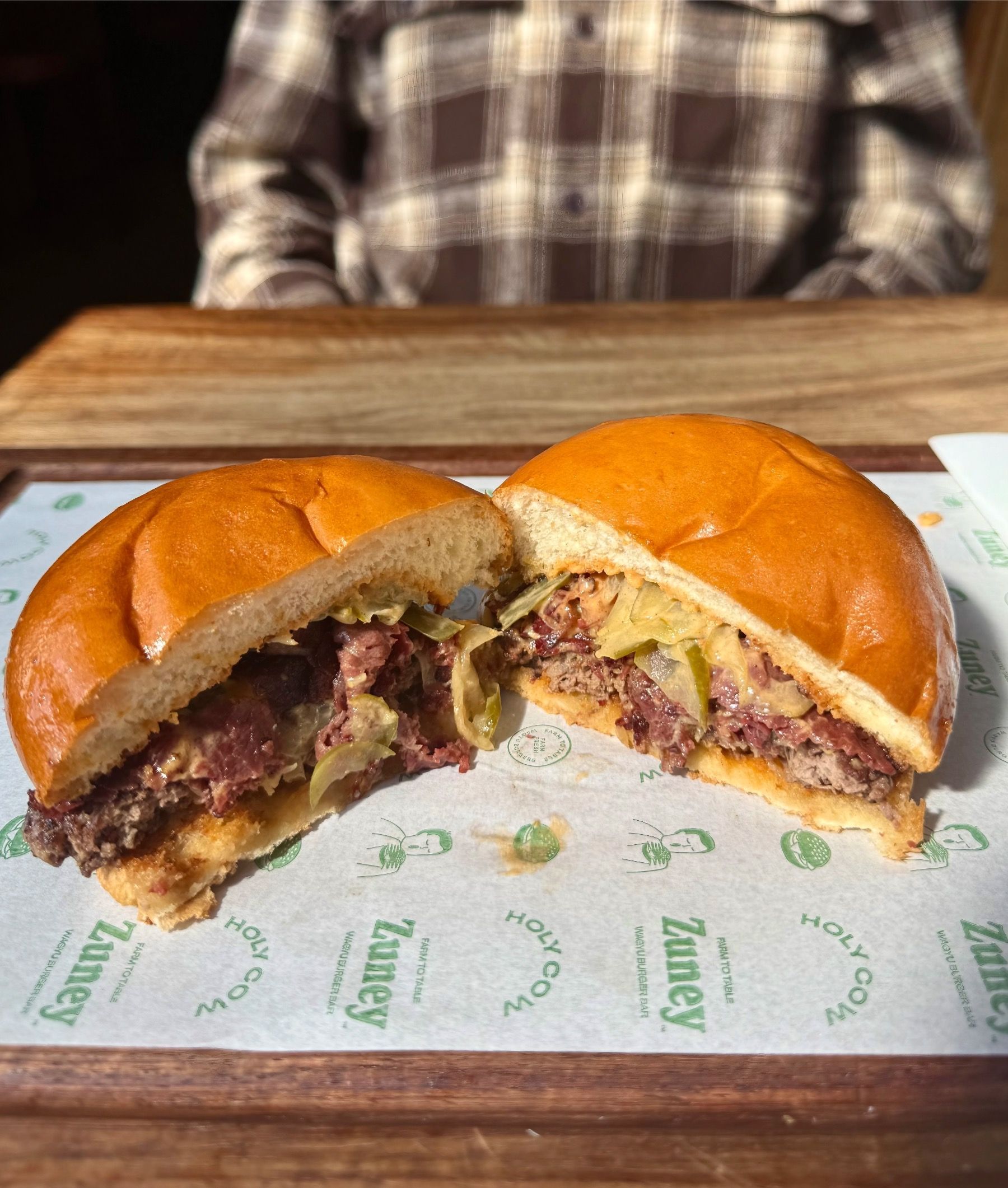 Close-up of Zuney wacon cheeseburger sliced open on wooden table