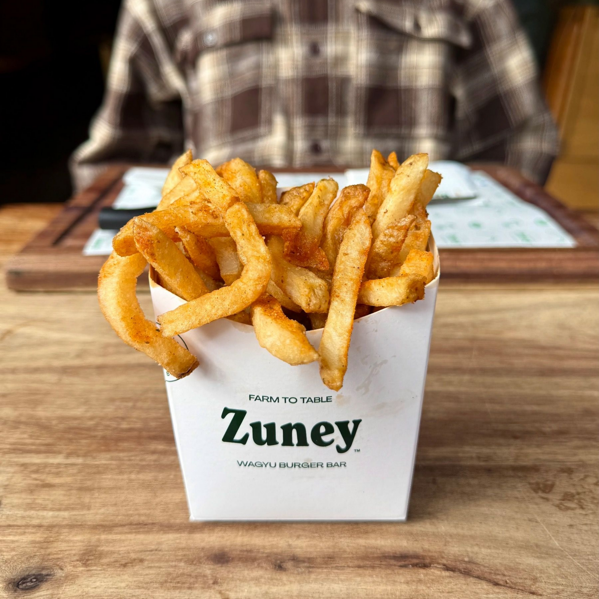 Classic salted fries in Zuney branded cup on wooden table

