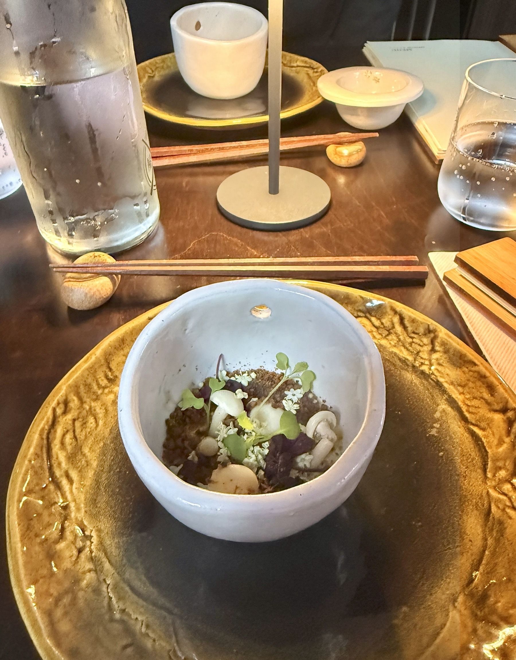 Yatai Ramen Bar amuse-bouche with marinated mushroom and delicate garnishes in ceramic bowl
