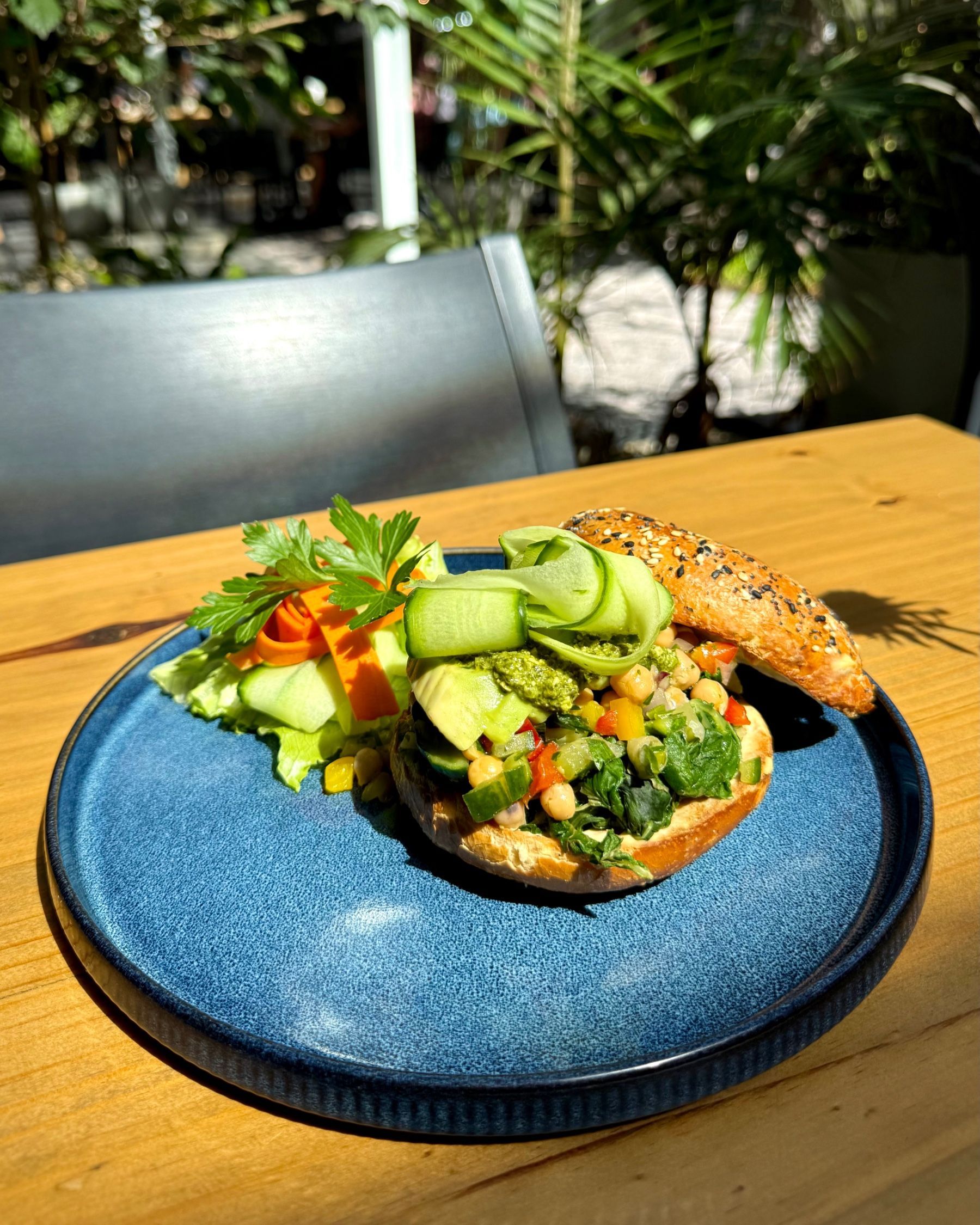 Yumcious vegan garbanzo bagel with hummus chickpeas avocado spinach on seeded bagel
