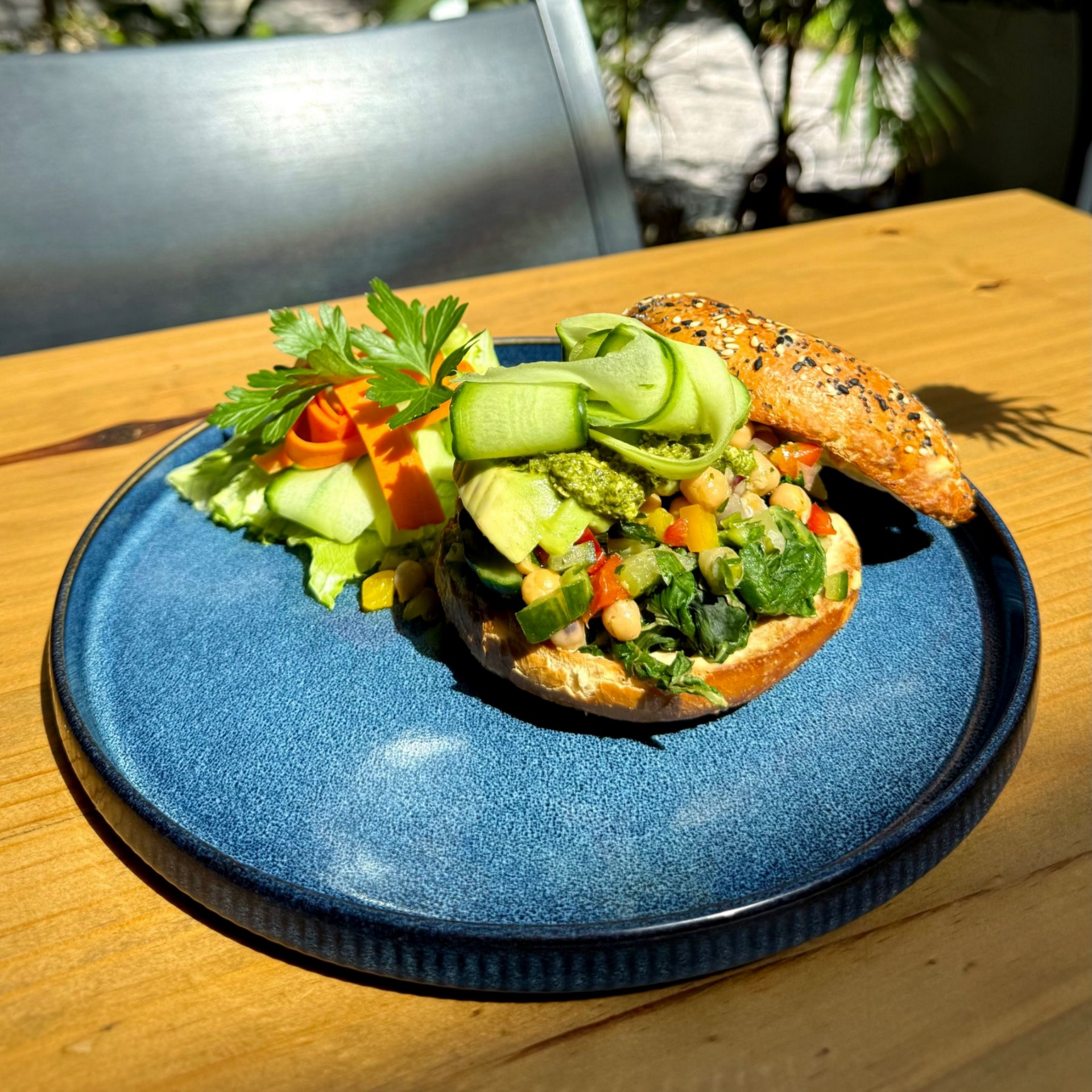 Yumcious vegan garbanzo bagel with hummus chickpeas avocado spinach on seeded bagel
