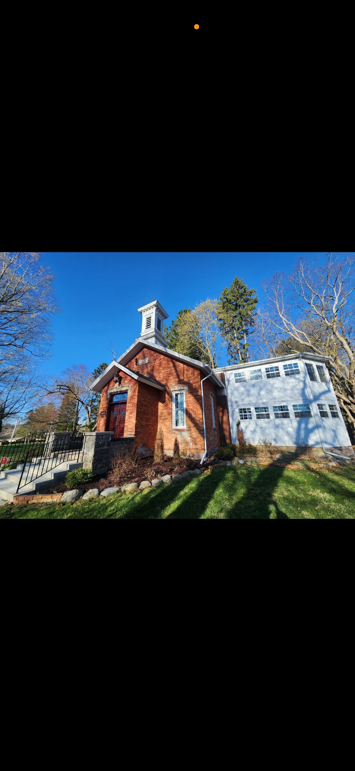 A small brick church is sitting on top of a hill next to a garage.