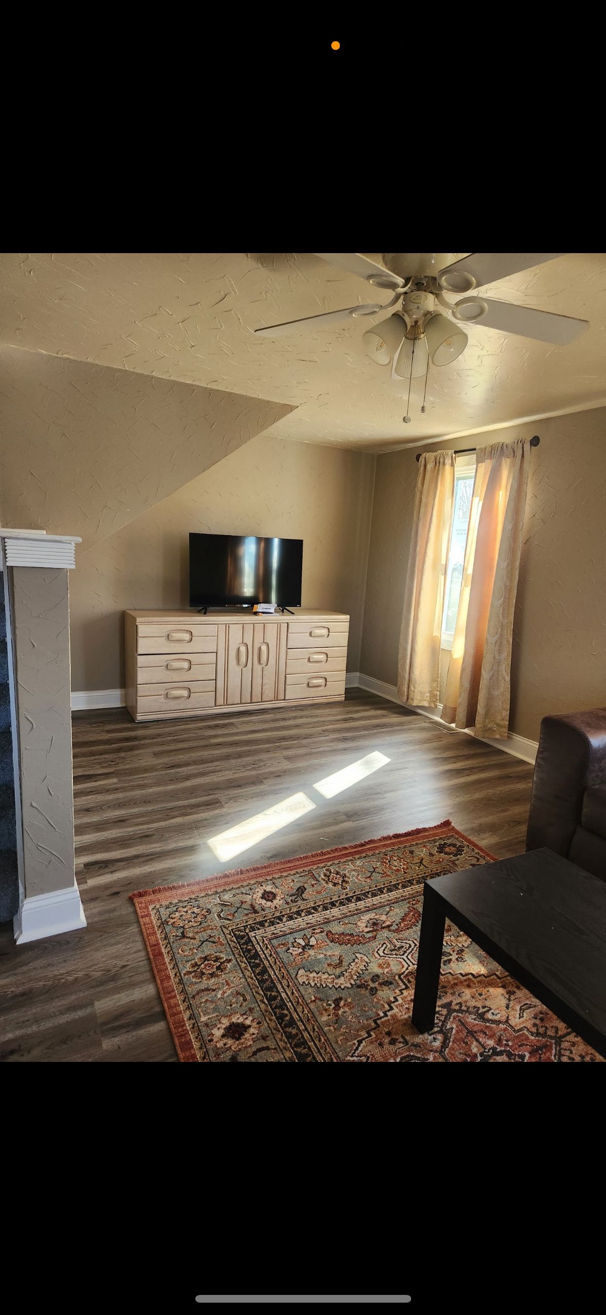 A living room with a couch , table , television and ceiling fan.