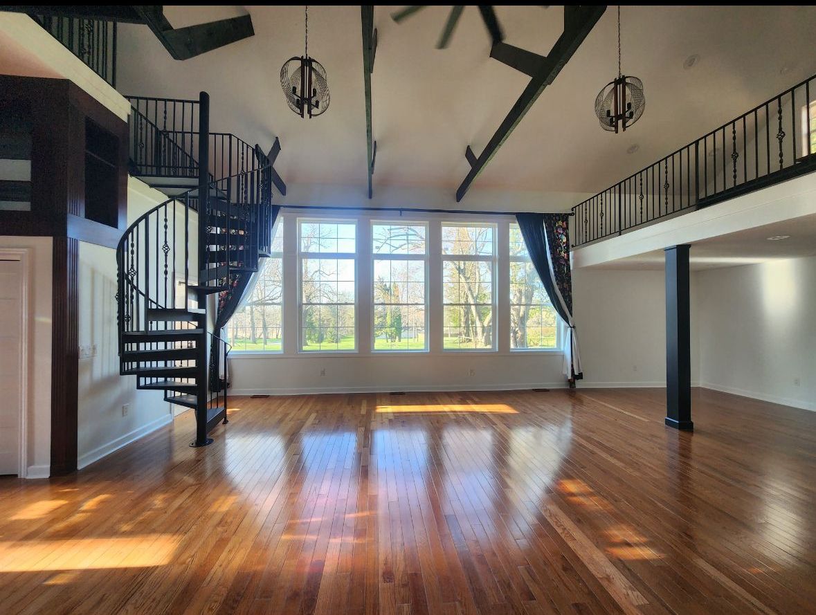 An empty room with a spiral staircase and lots of windows
