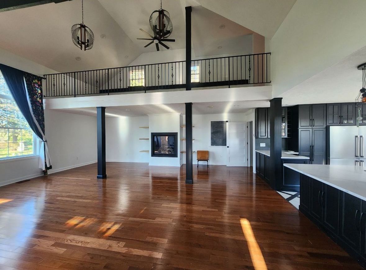 A large empty room with hardwood floors and a ceiling fan.