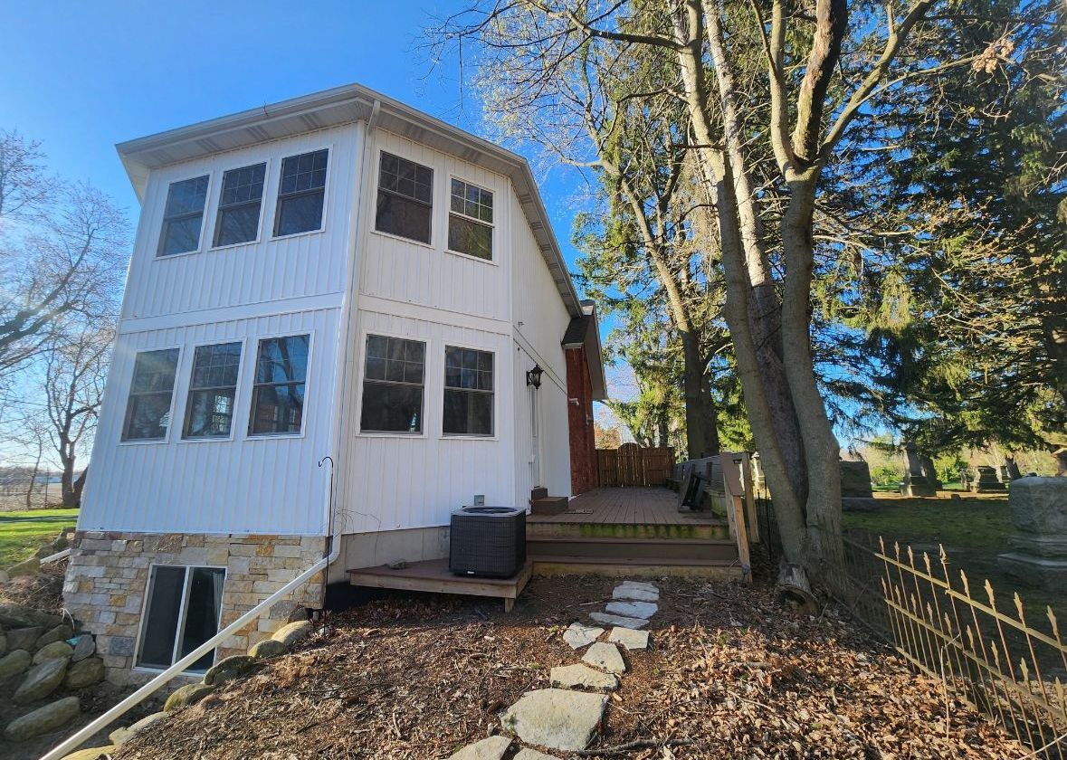 A white house with a lot of windows is surrounded by trees.